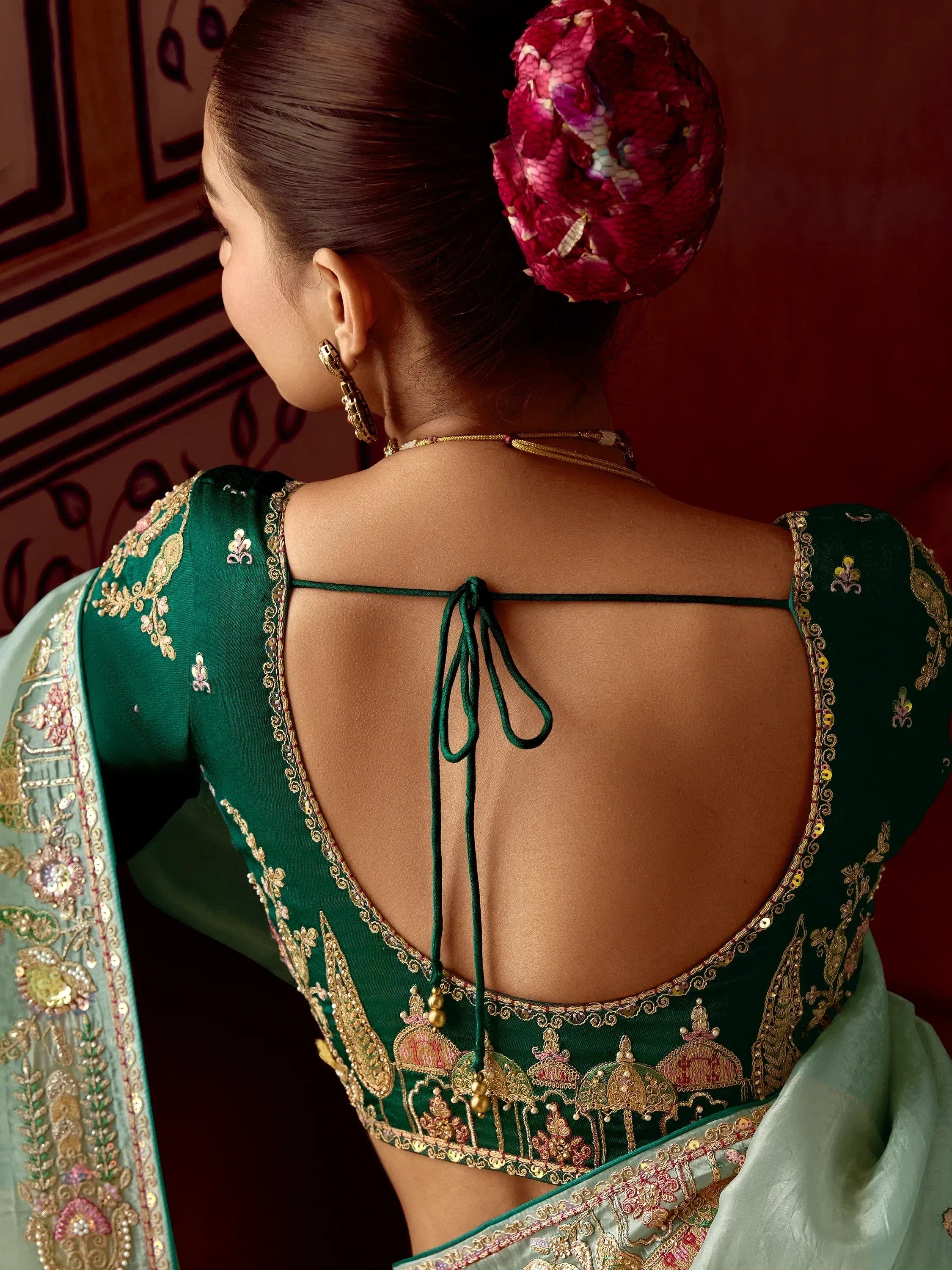 Green embroidered saree blouse with back tie and floral hair accessory