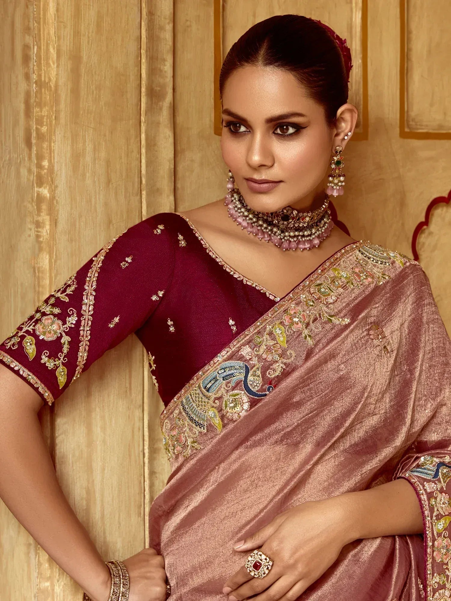 Elegant maroon and rose saree with intricate floral embroidery and traditional jewelry