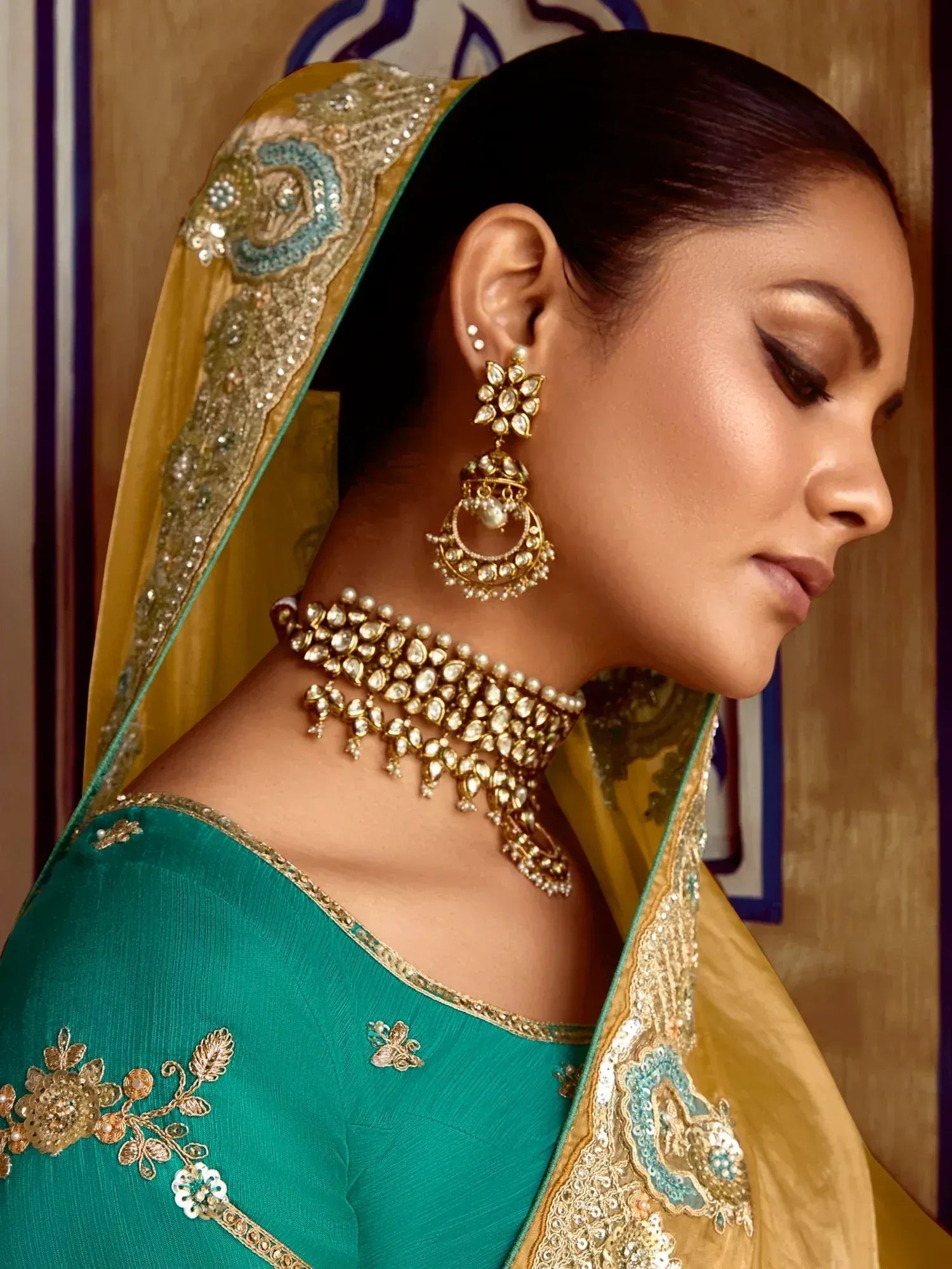 Elegant woman in teal lehenga choli with gold embroidery and traditional jewelry