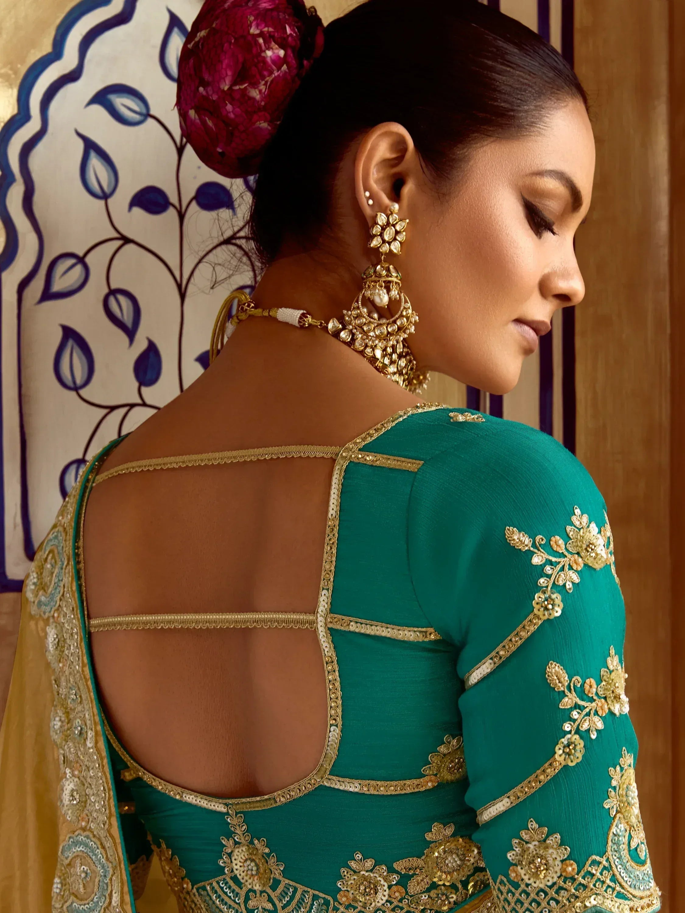 Teal ethnic gown with gold embroidery and open back design, paired with traditional jewelry