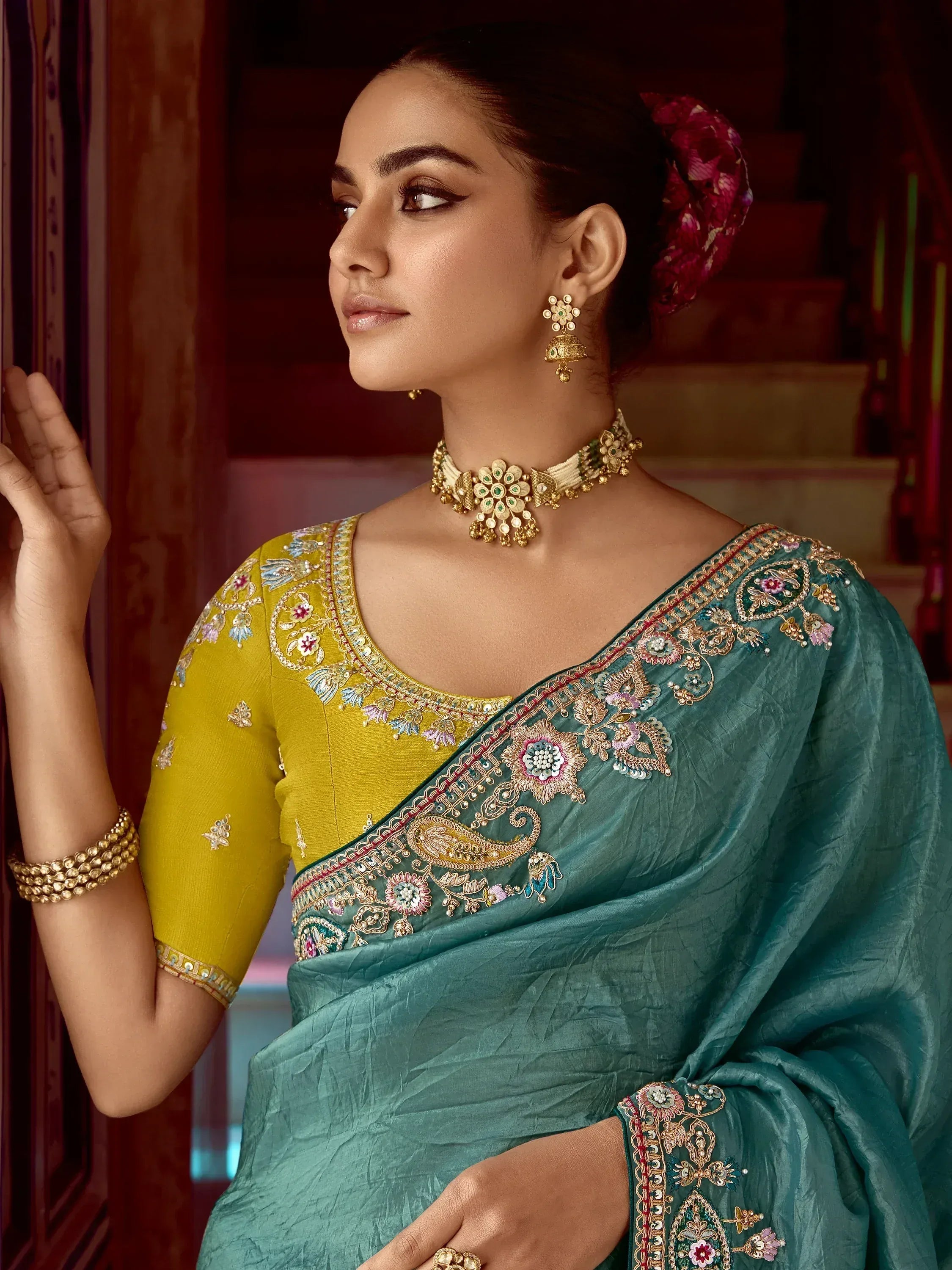 Elegant teal saree with floral embroidery, paired with a yellow blouse and gold jewelry for Indian ethnic wear.