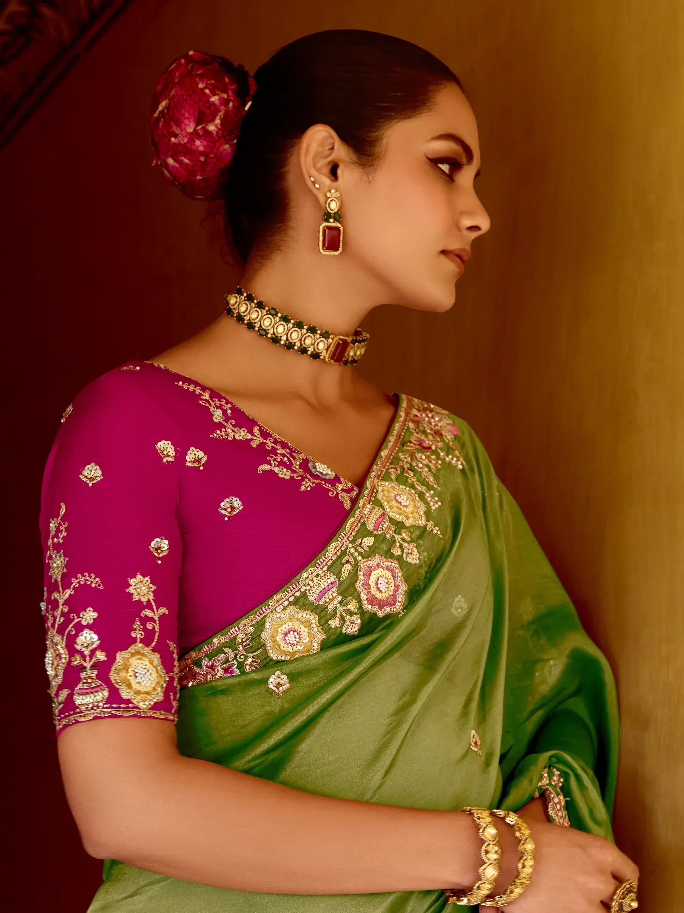 Elegant green saree with pink blouse, intricate gold embroidery, and traditional jewelry