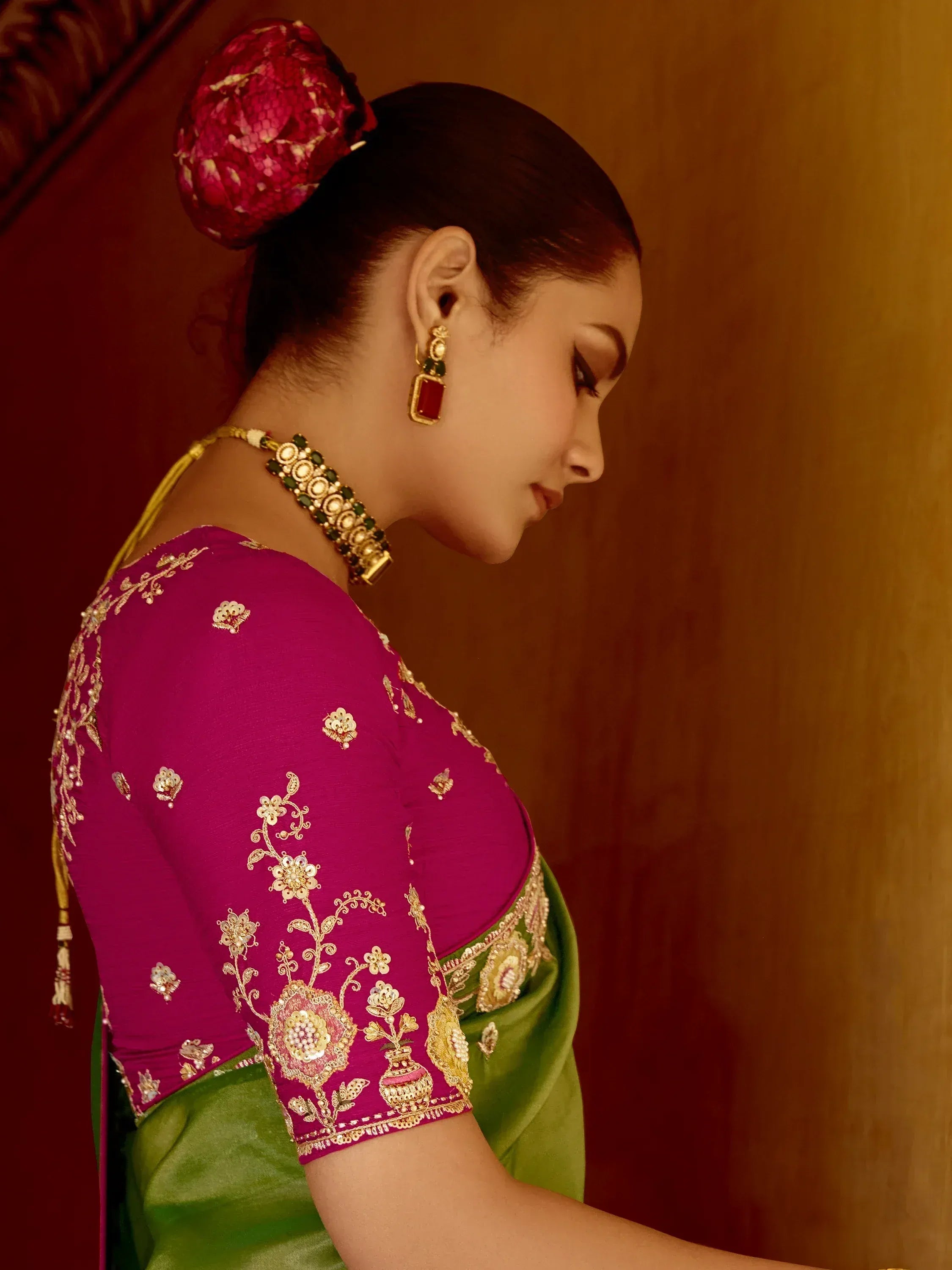 Elegant woman in purple and green saree with gold floral embroidery and traditional jewelry