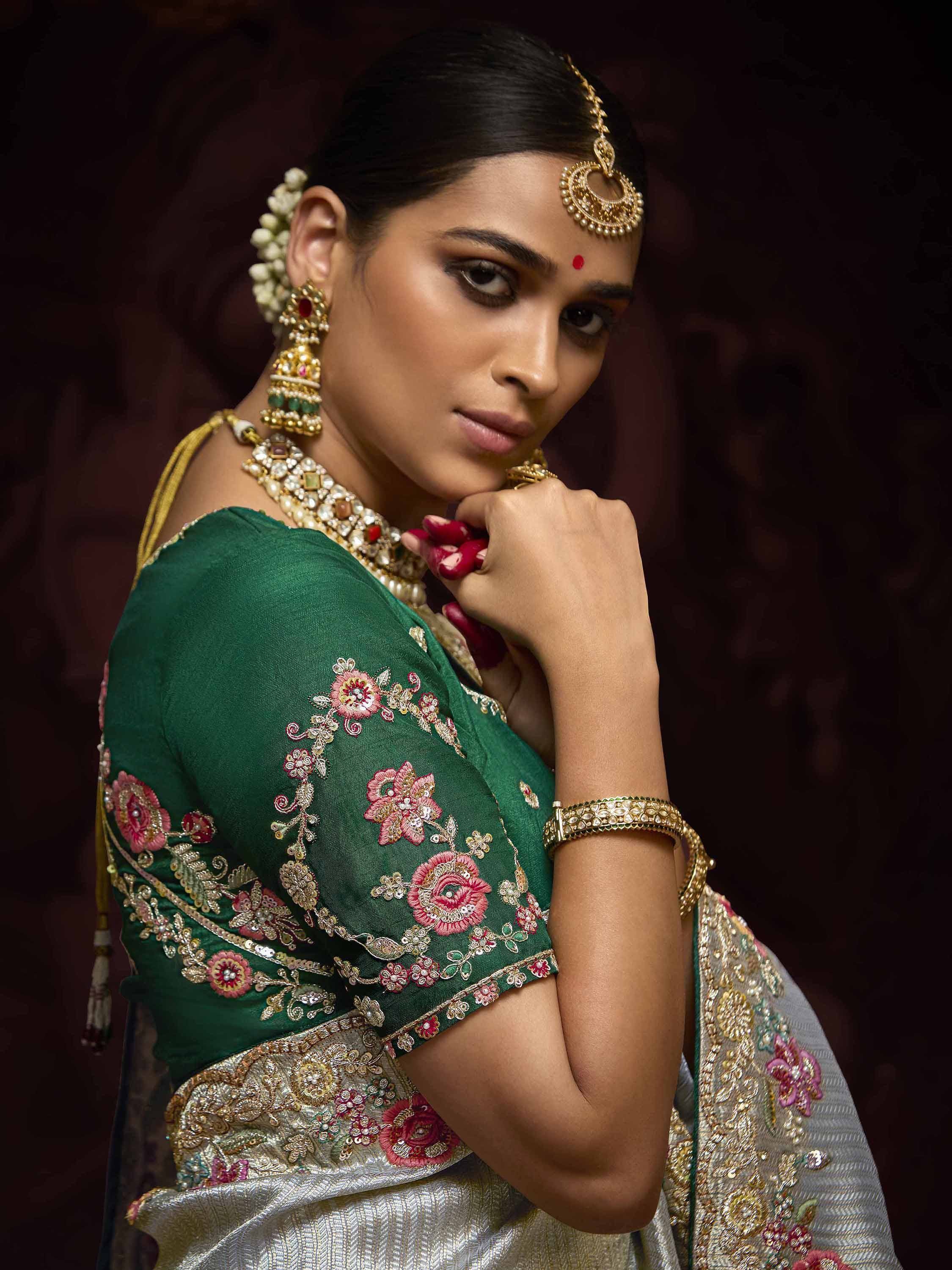 Elegant woman in green embroidered saree with gold jewelry, traditional Indian ethnic wear