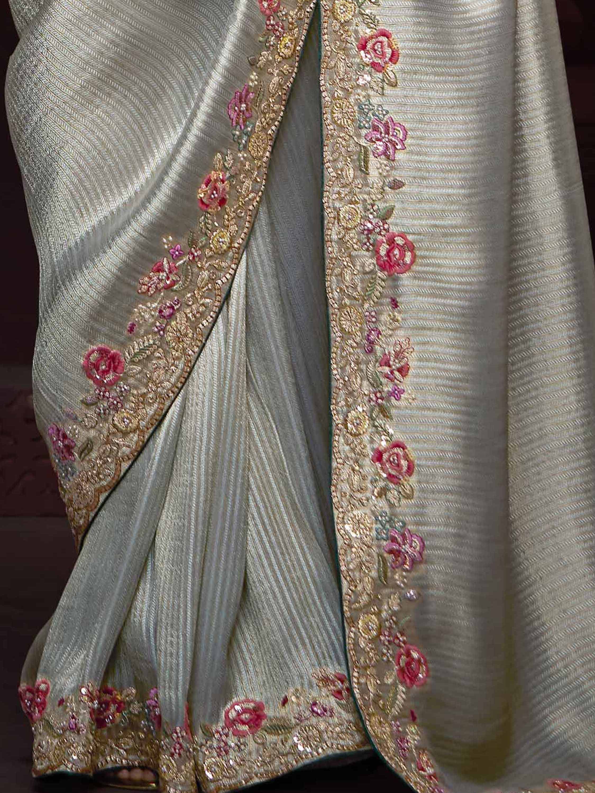 Elegant silver saree with pink floral embroidery and gold zari work, perfect for Indian ethnic occasions.