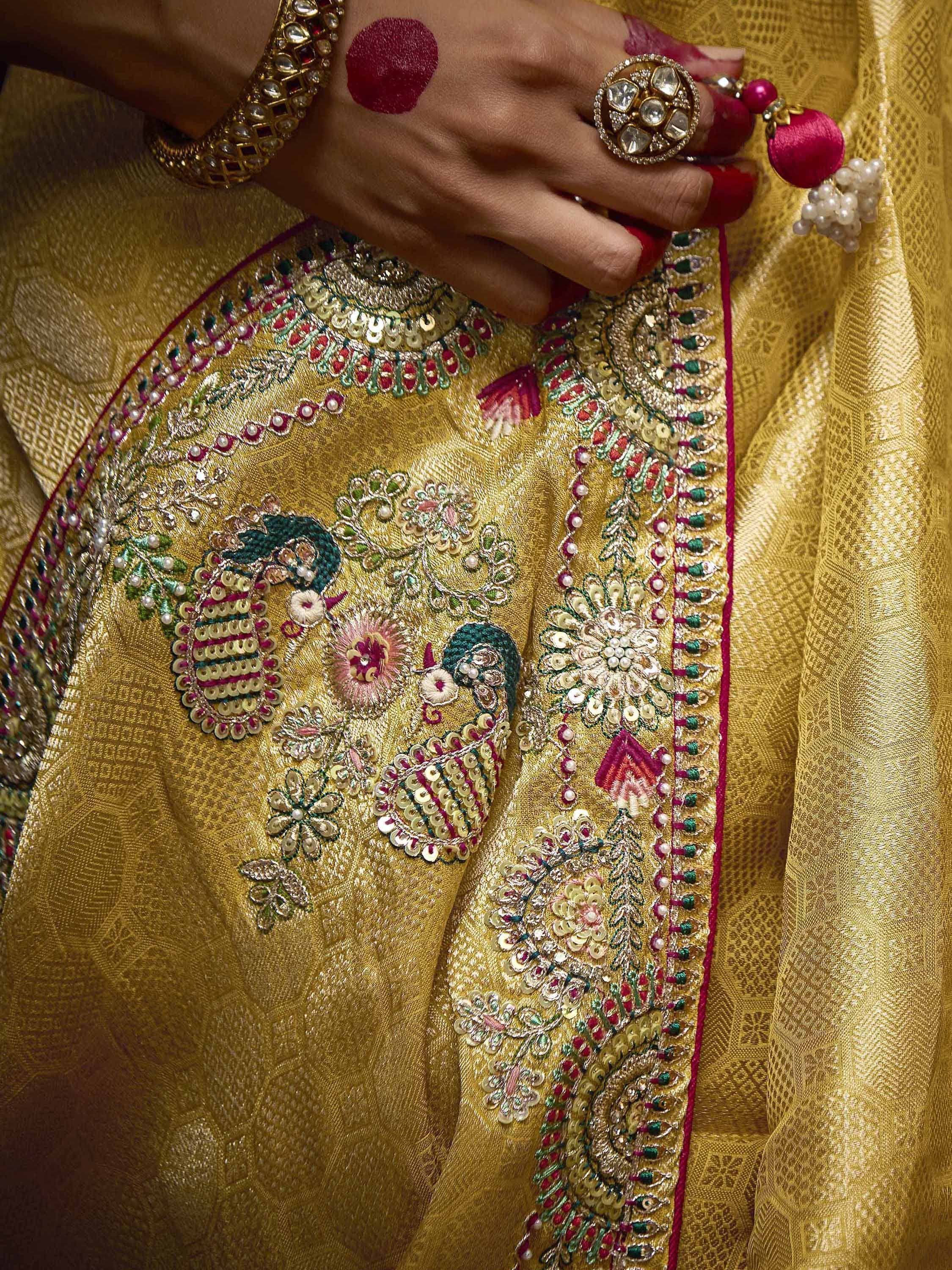 Golden ethnic lehenga with peacock embroidery, sequins, and traditional jewelry for Indian weddings.