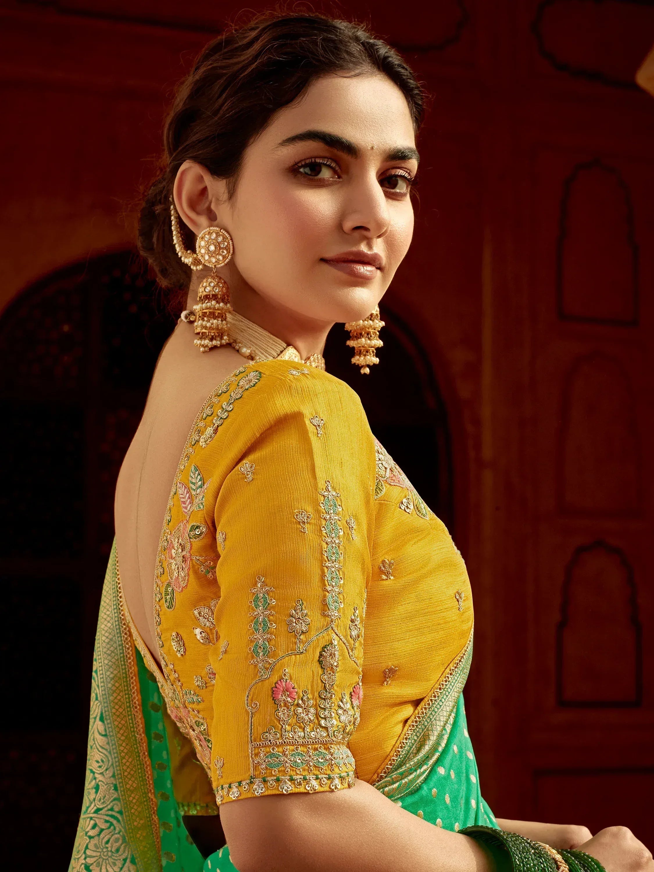 Elegant woman in yellow embroidered blouse with green saree, traditional Indian ethnic wear, designer jewelry