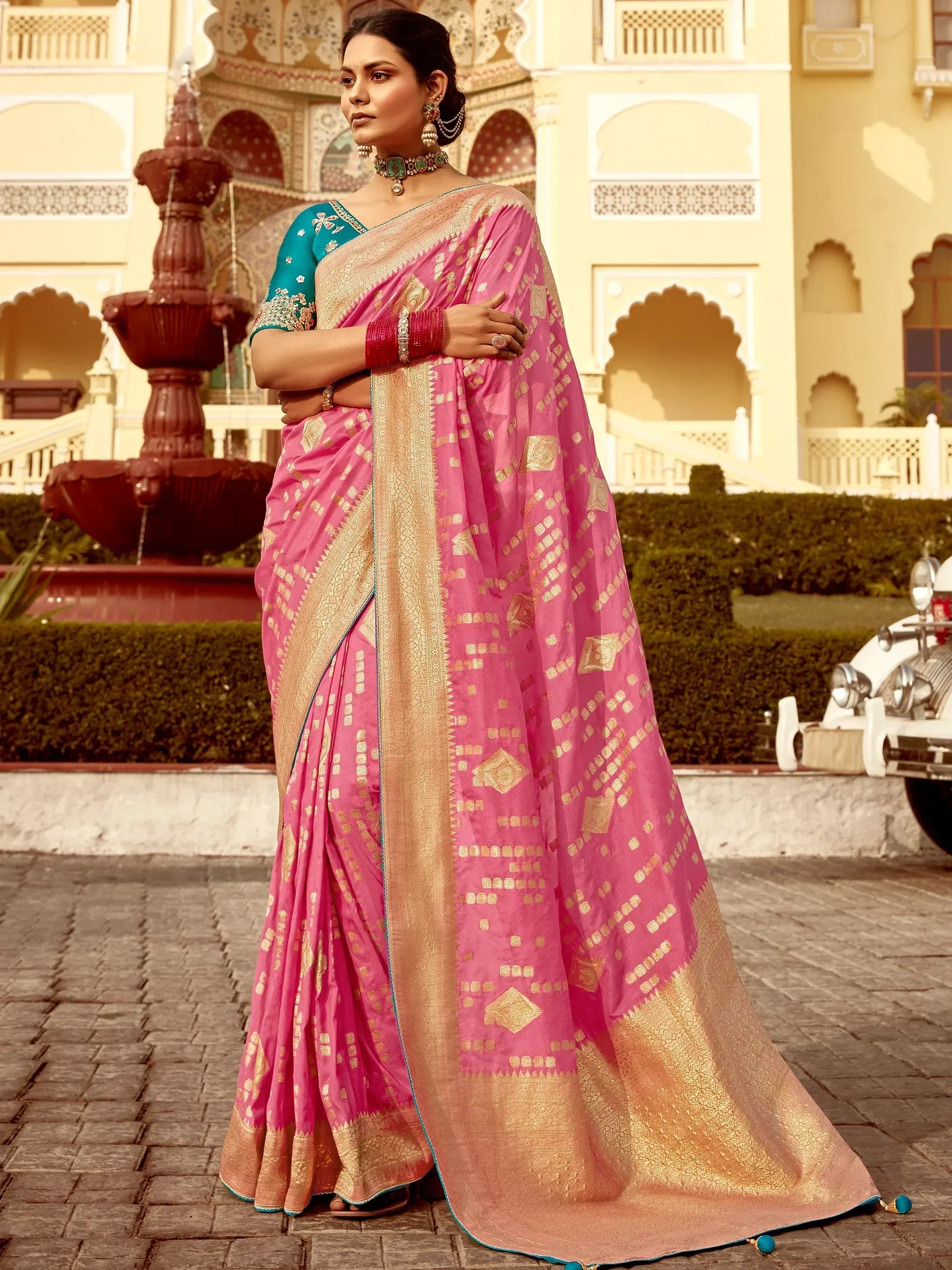 Pink and gold designer saree with intricate patterns, paired with teal blouse, perfect for ethnic occasions.