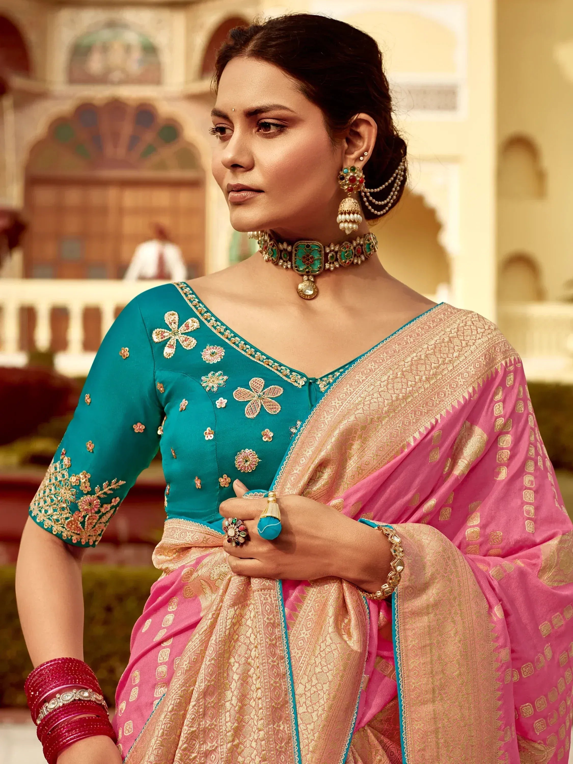 Elegant woman in teal floral blouse and pink saree with gold embroidery, traditional Indian ethnic wear