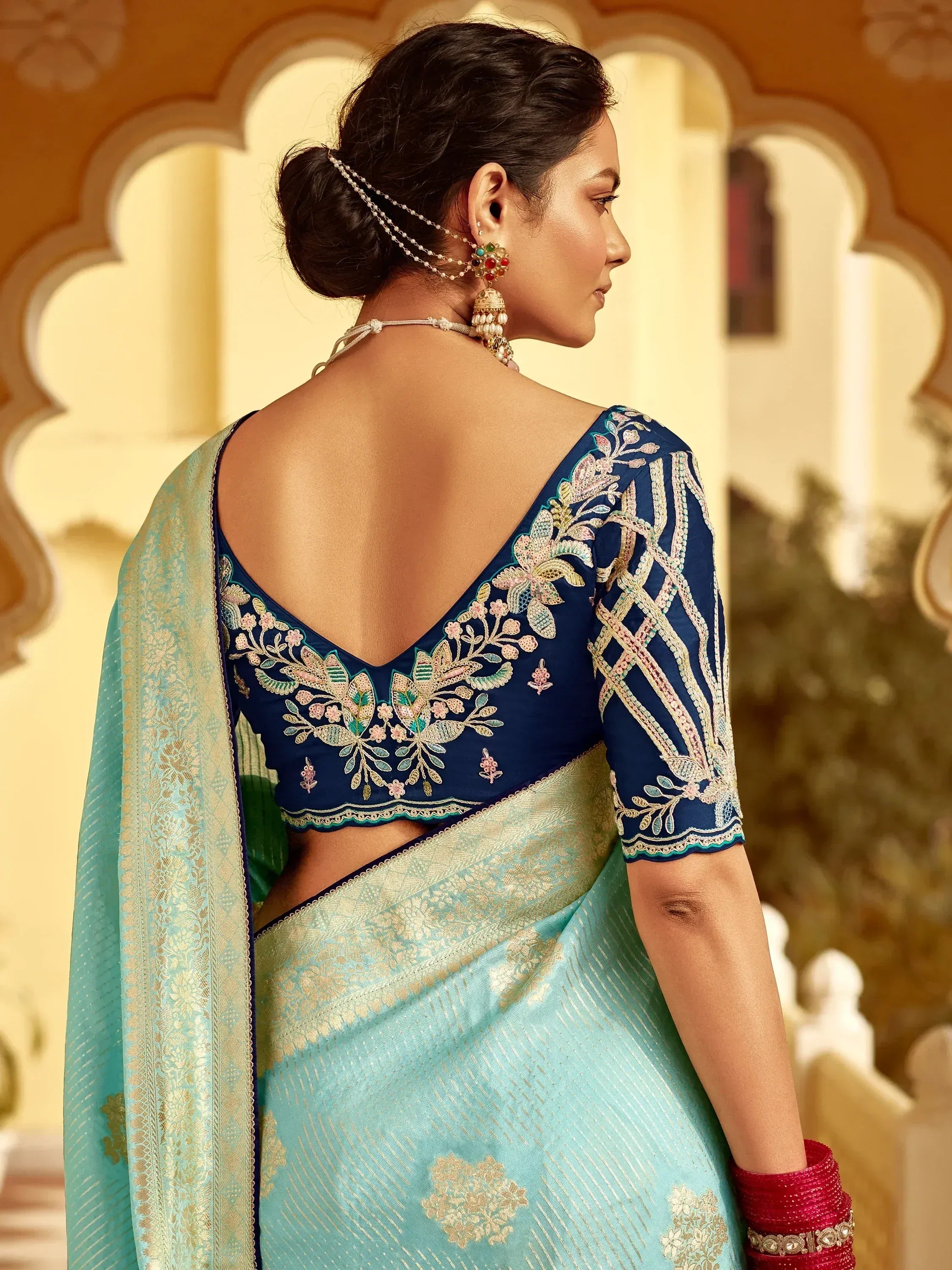 Elegant blue embroidered blouse with floral design paired with light blue saree, perfect for Indian ethnic wear.