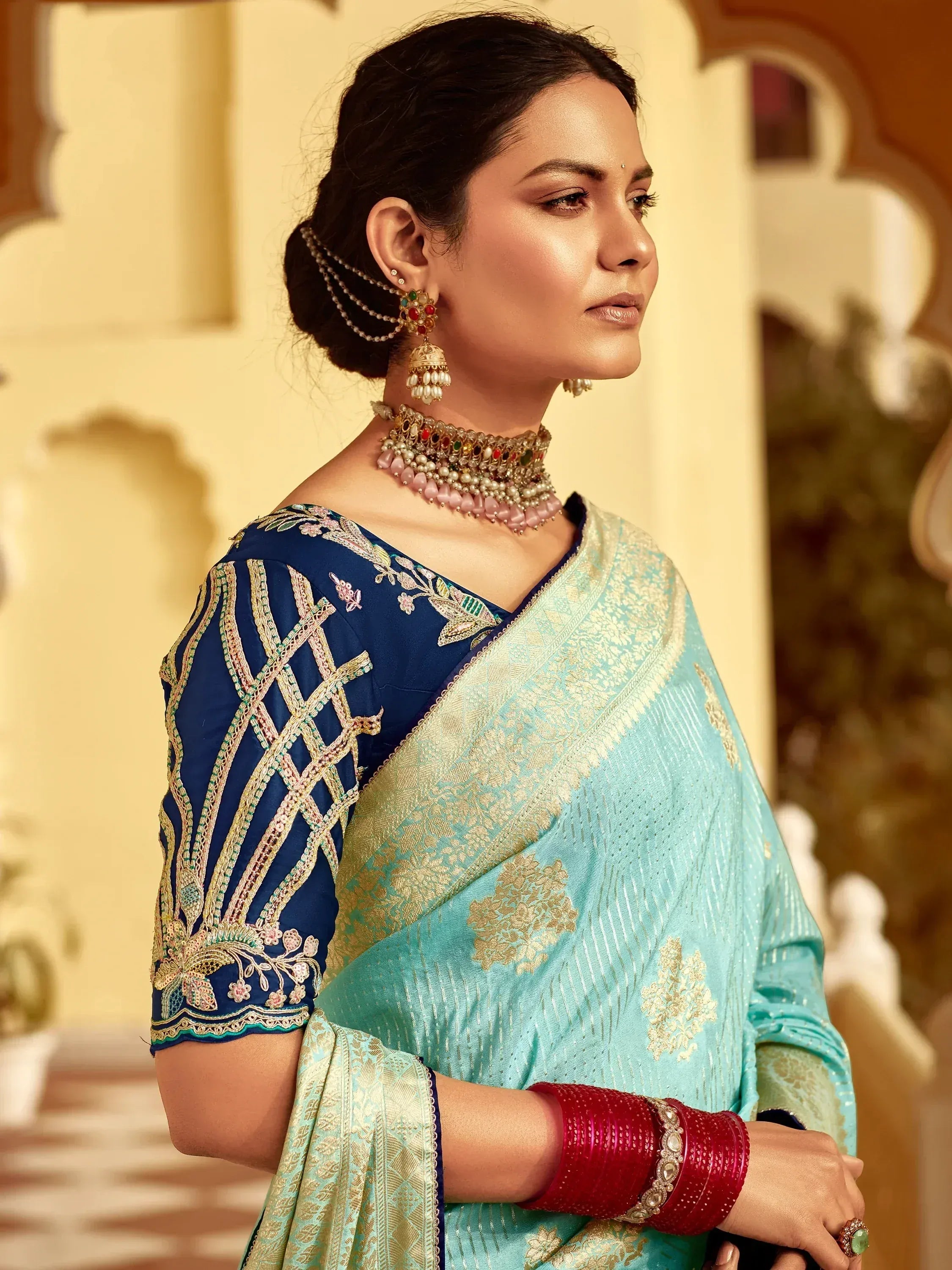 Elegant turquoise saree with gold embroidery and navy blue blouse, paired with traditional jewelry.