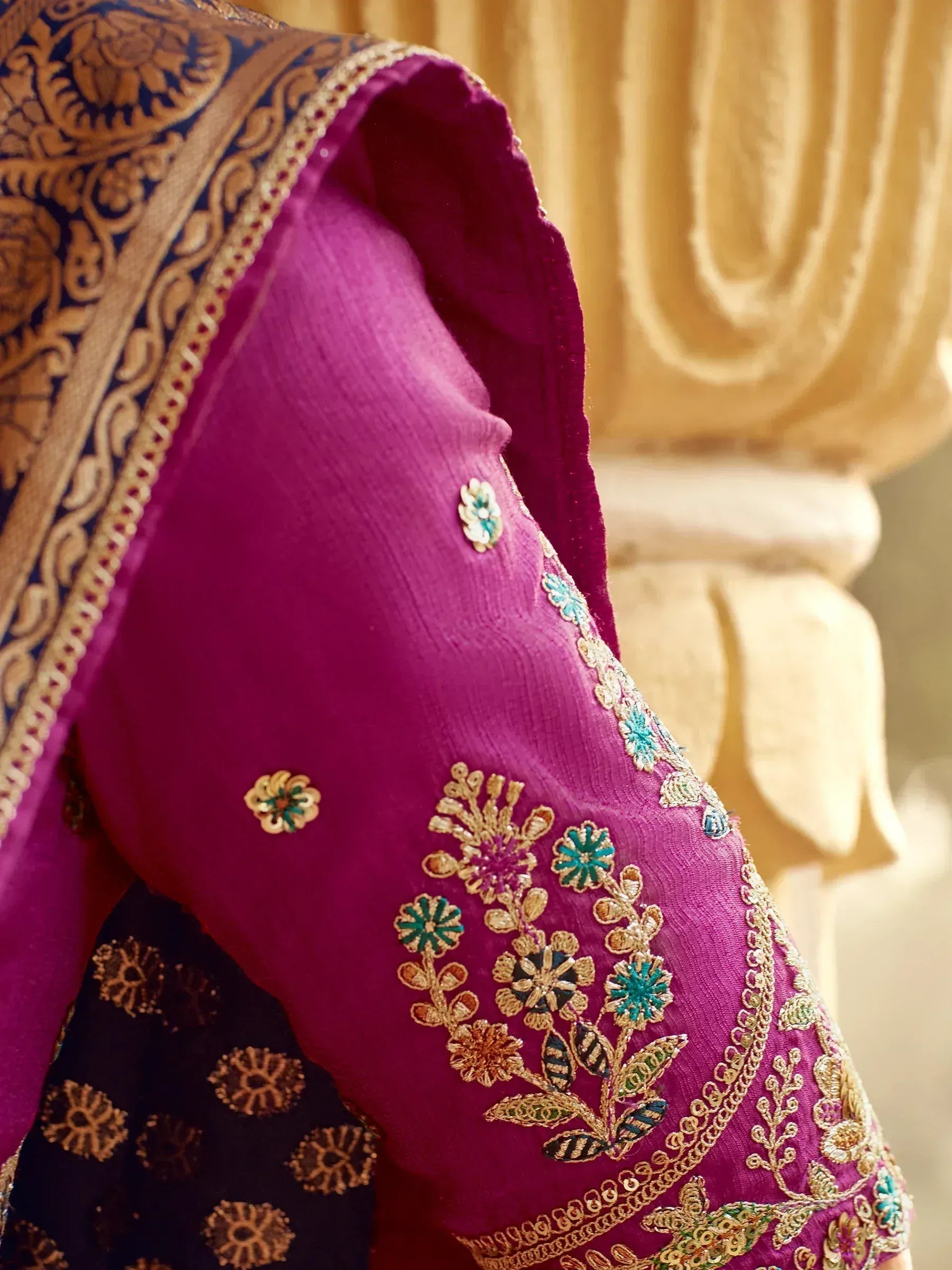 Magenta ethnic blouse with floral embroidery and gold detailing, paired with a navy dupatta.