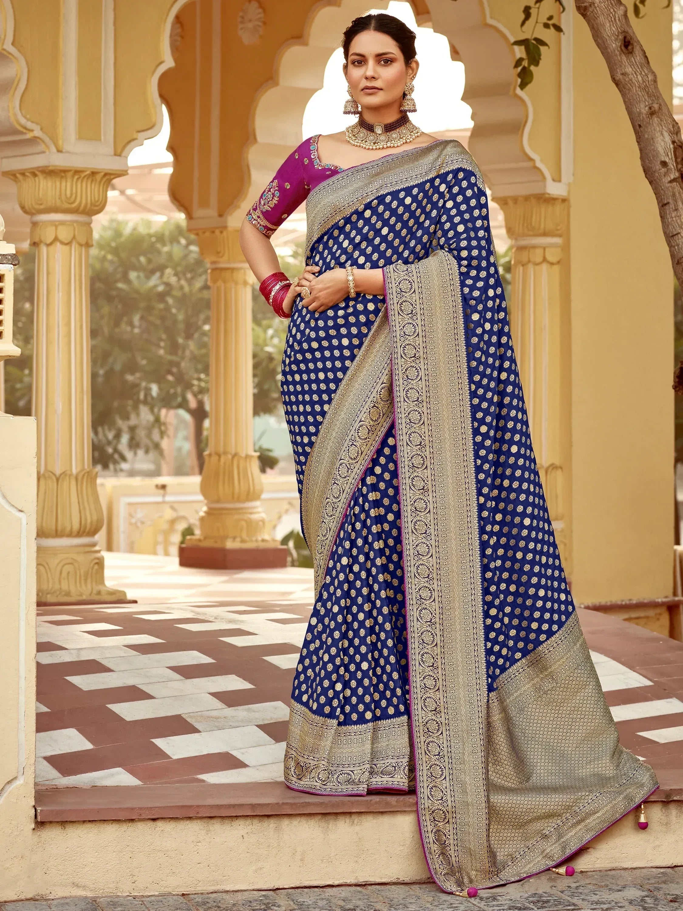 Royal blue saree with gold floral print and intricate border, paired with purple blouse, perfect for Indian ethnic occasions.