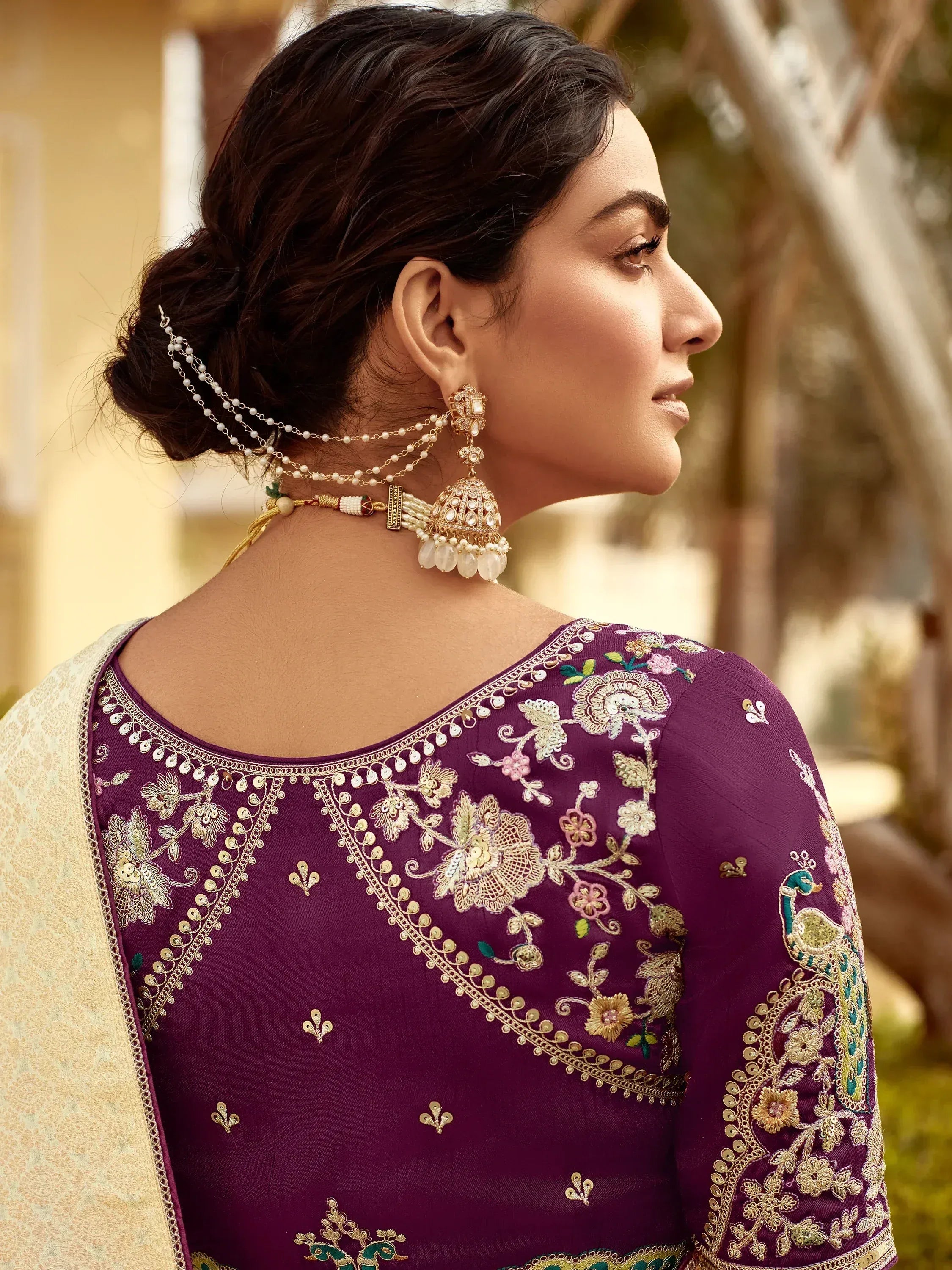 Purple embroidered ethnic gown with floral and peacock designs, paired with traditional jewelry