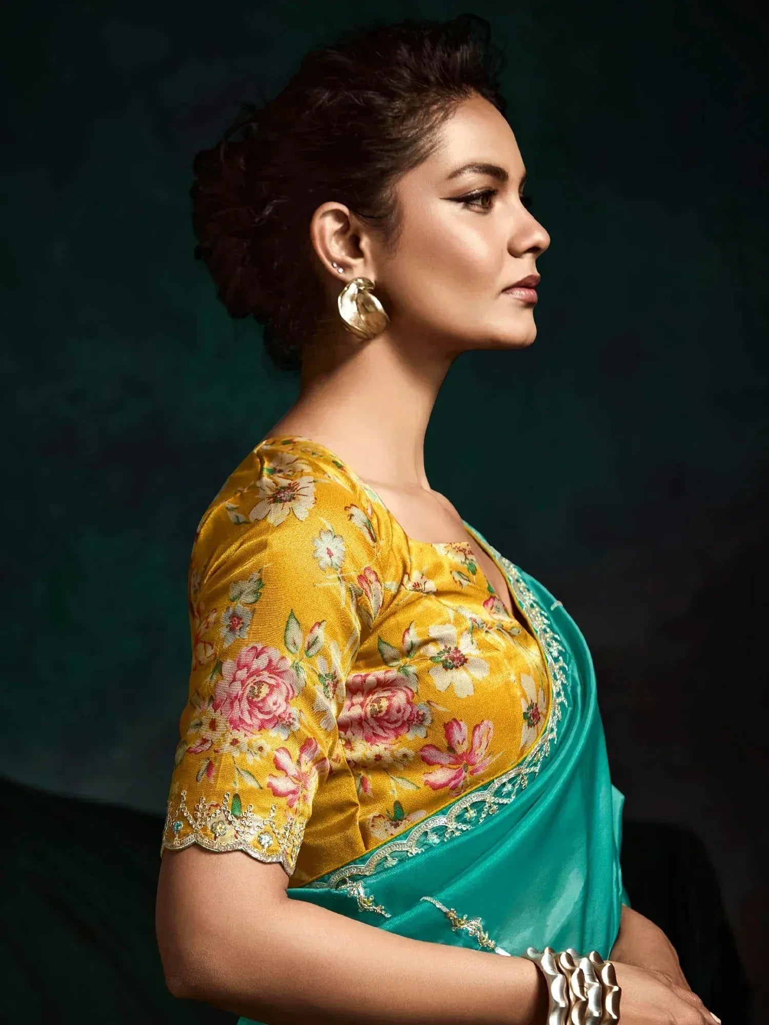 Woman in floral yellow blouse and teal saree, ethnic Indian wear with gold embroidery