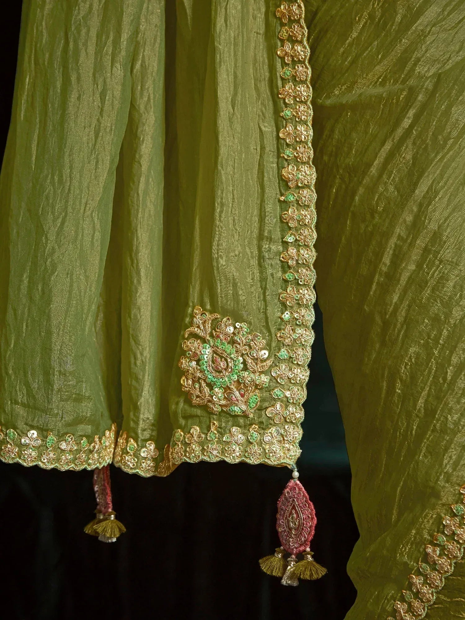 Olive green ethnic saree with gold floral embroidery, green sequins, and pink tassels
