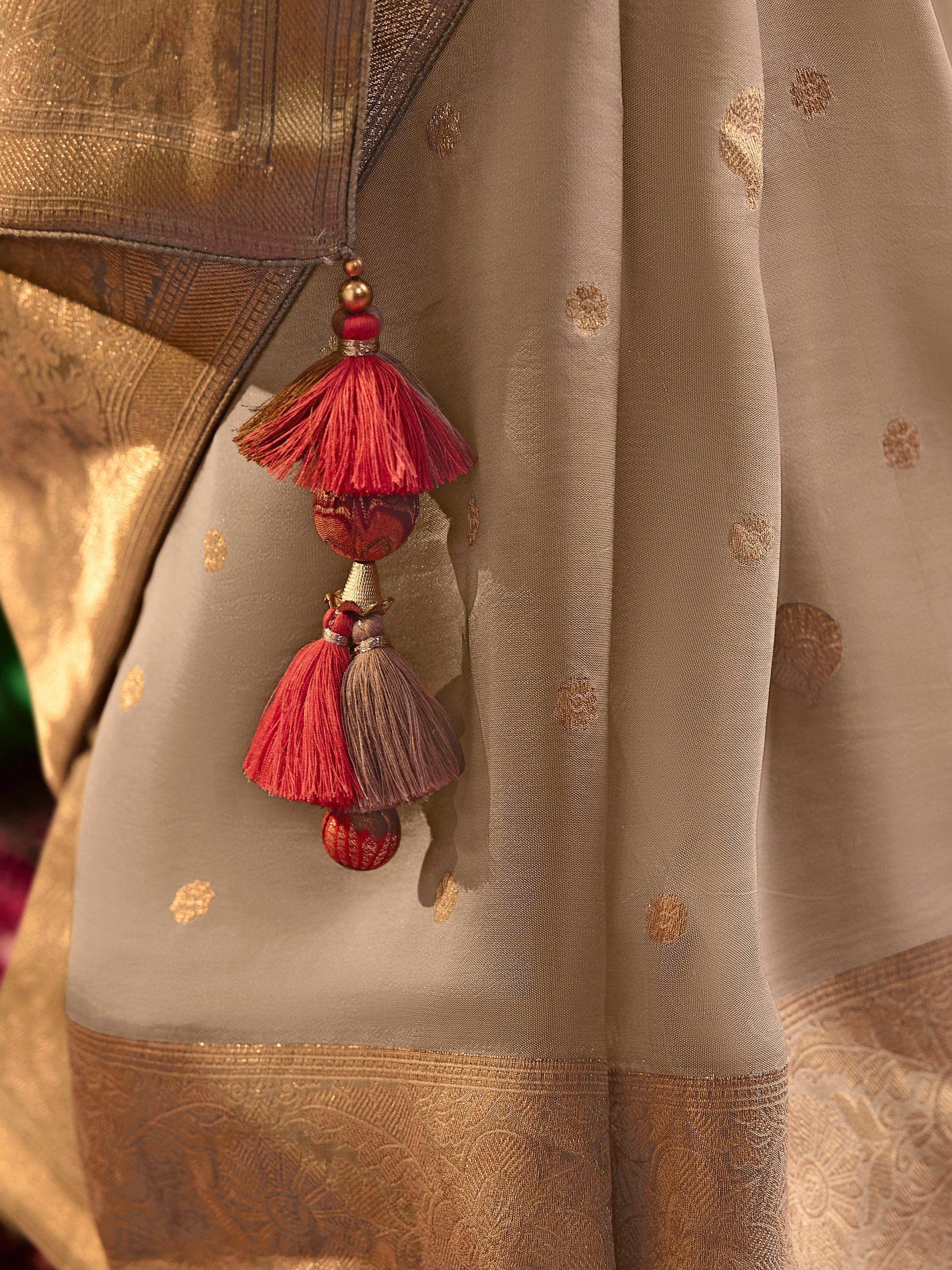 Elegant Indian ethnic wear with gold brocade, sheer dupatta, and red tassels for festive occasions