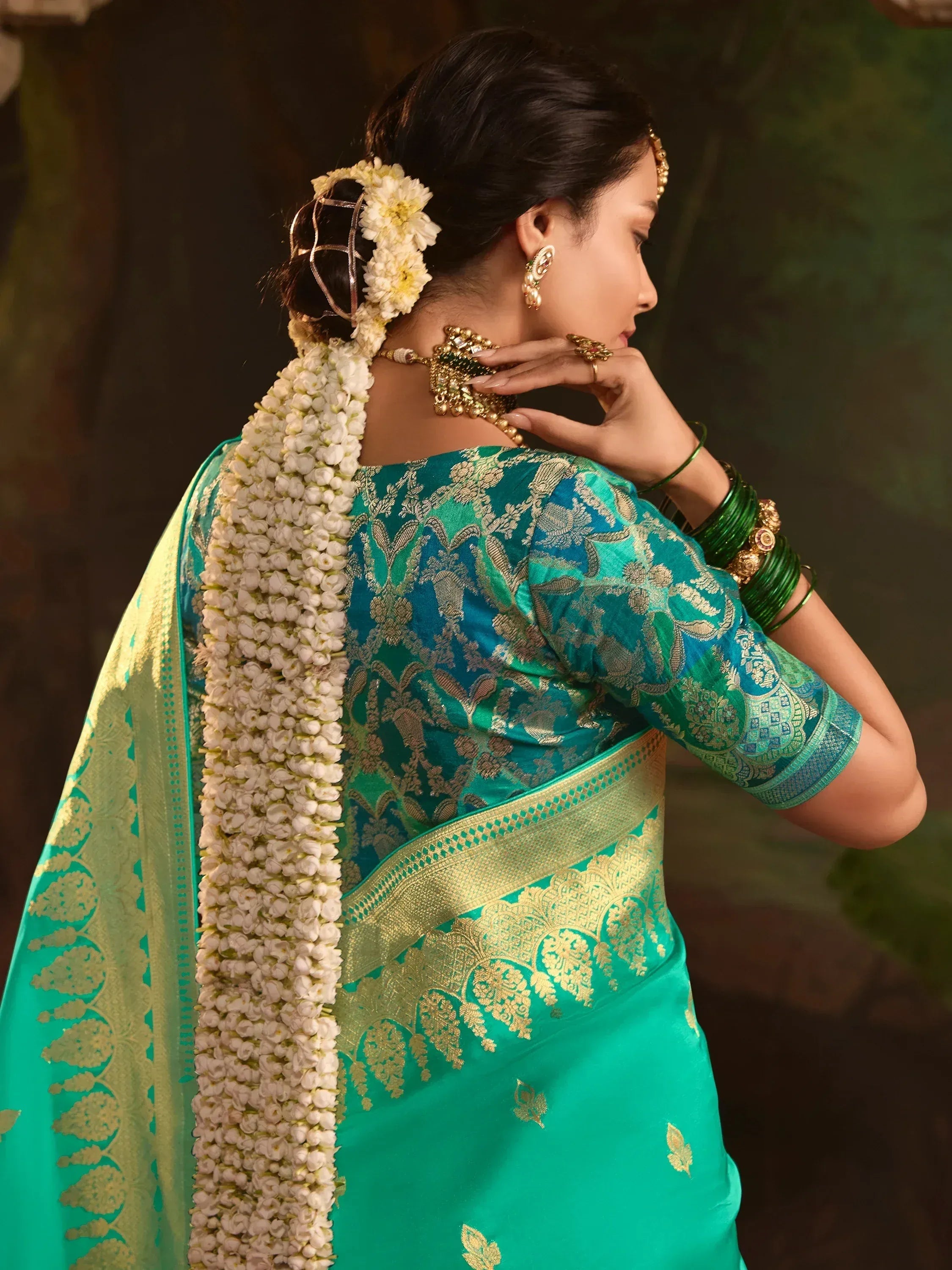 Teal designer saree with gold embroidery, floral hair adornment, and traditional jewelry for Indian ethnic wear