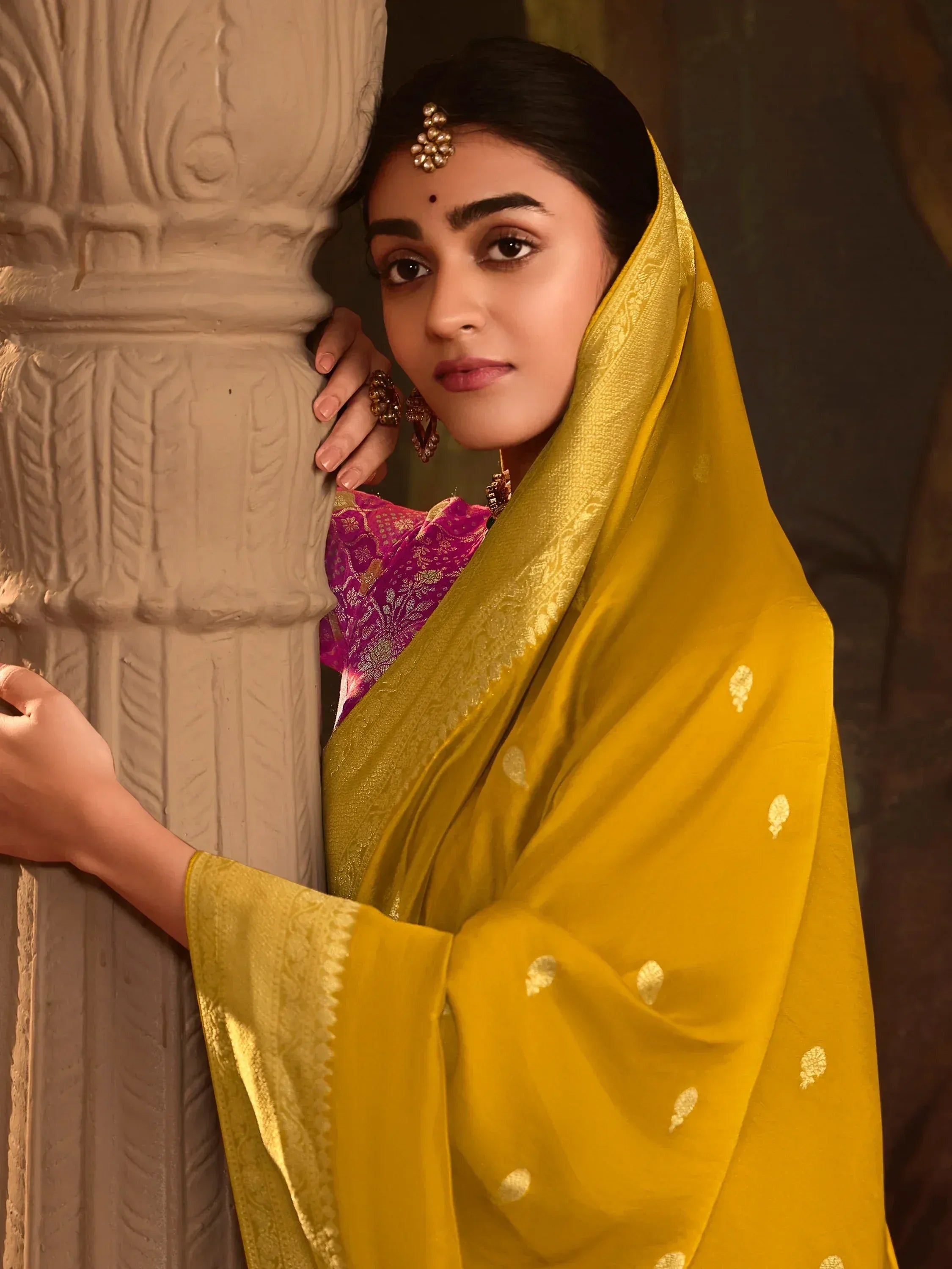 Woman in vibrant yellow saree with gold motifs, paired with pink blouse, traditional Indian ethnic wear