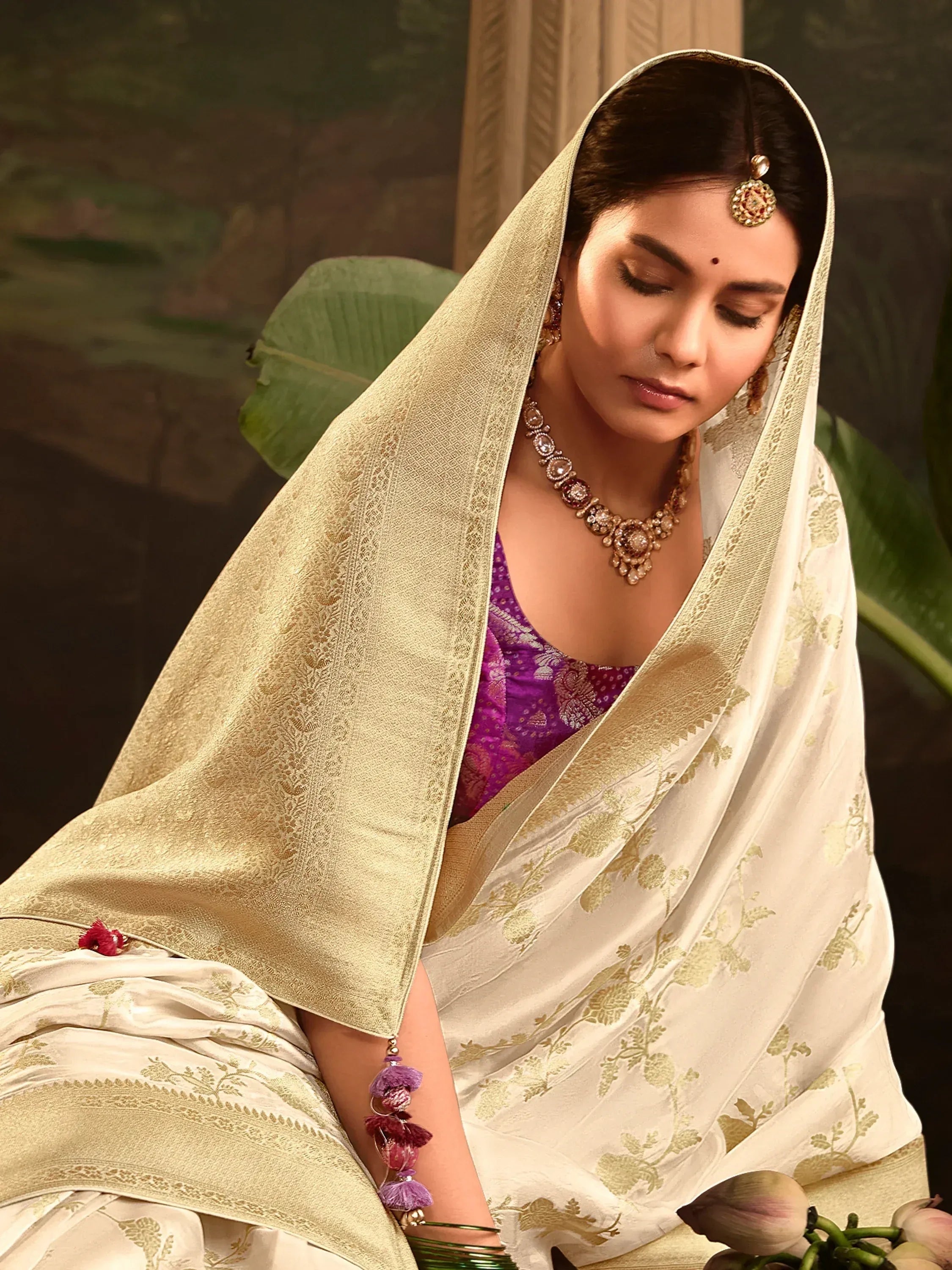 Elegant woman in white and gold floral saree with purple blouse, traditional Indian ethnic wear