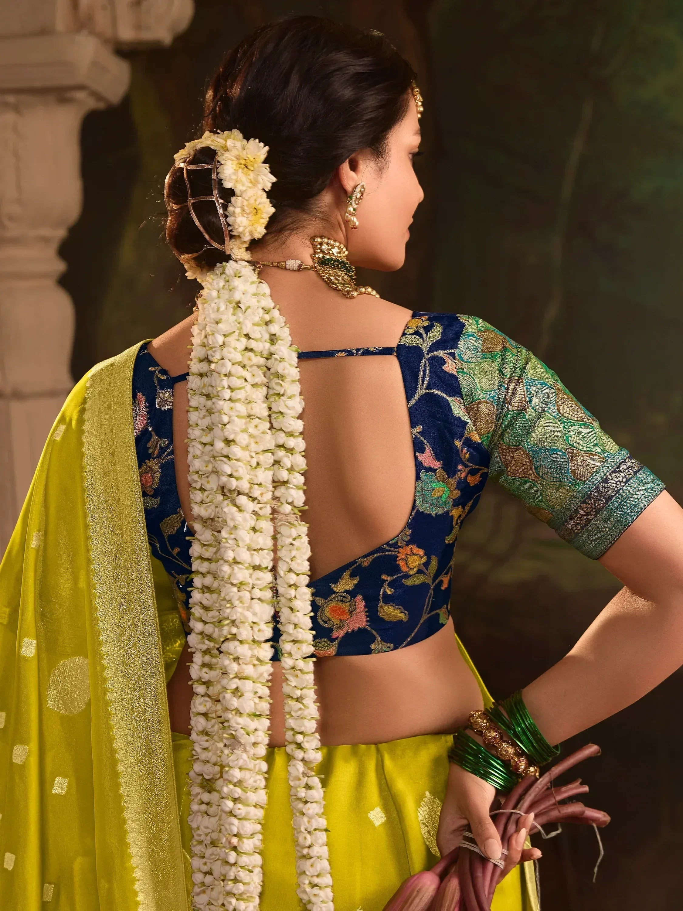 Woman in blue floral blouse & yellow saree with white flower garland, traditional Indian ethnic wear