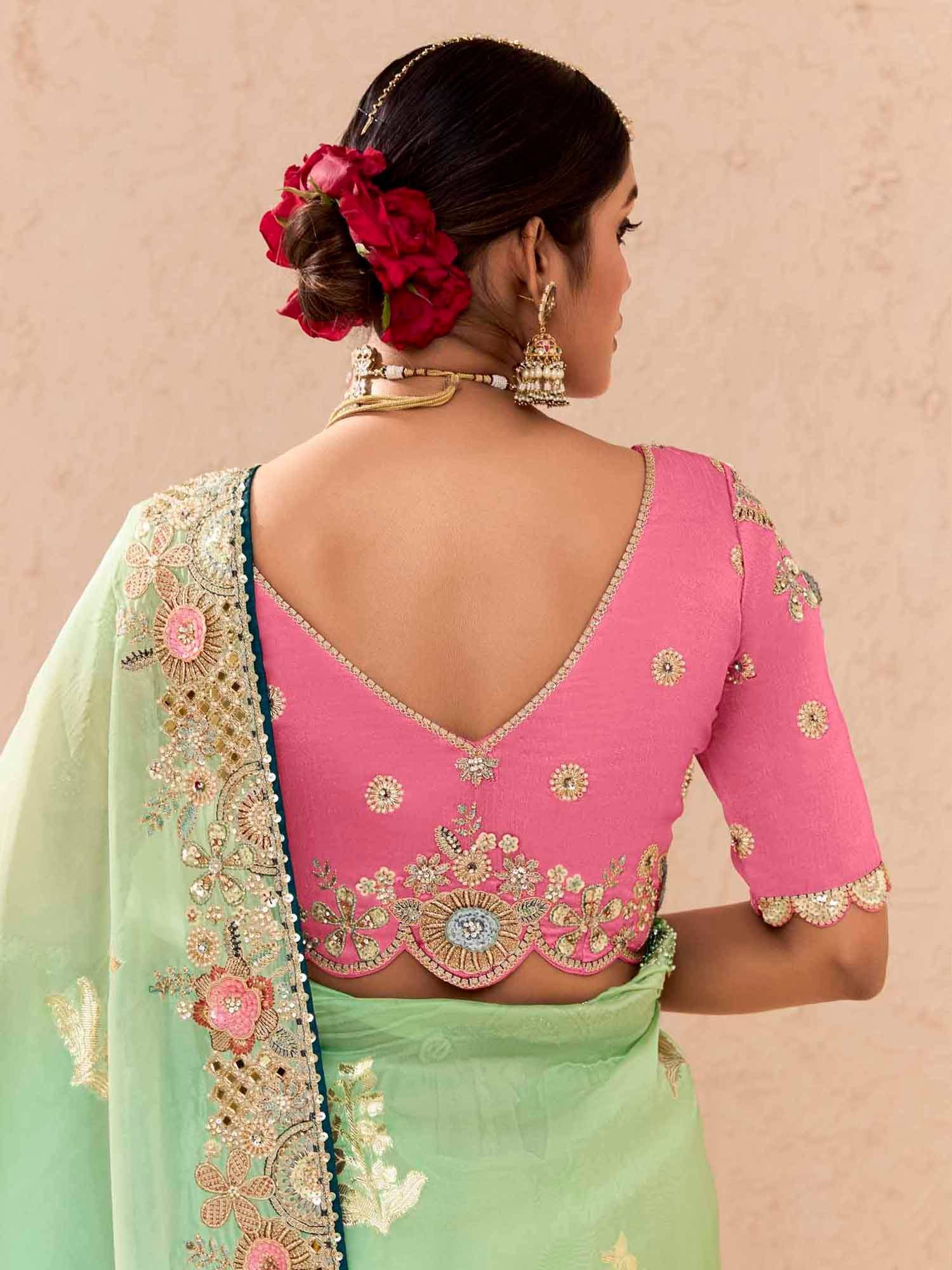 Pink embroidered blouse with green saree, floral hair accessory, and gold jewelry for Indian ethnic wear