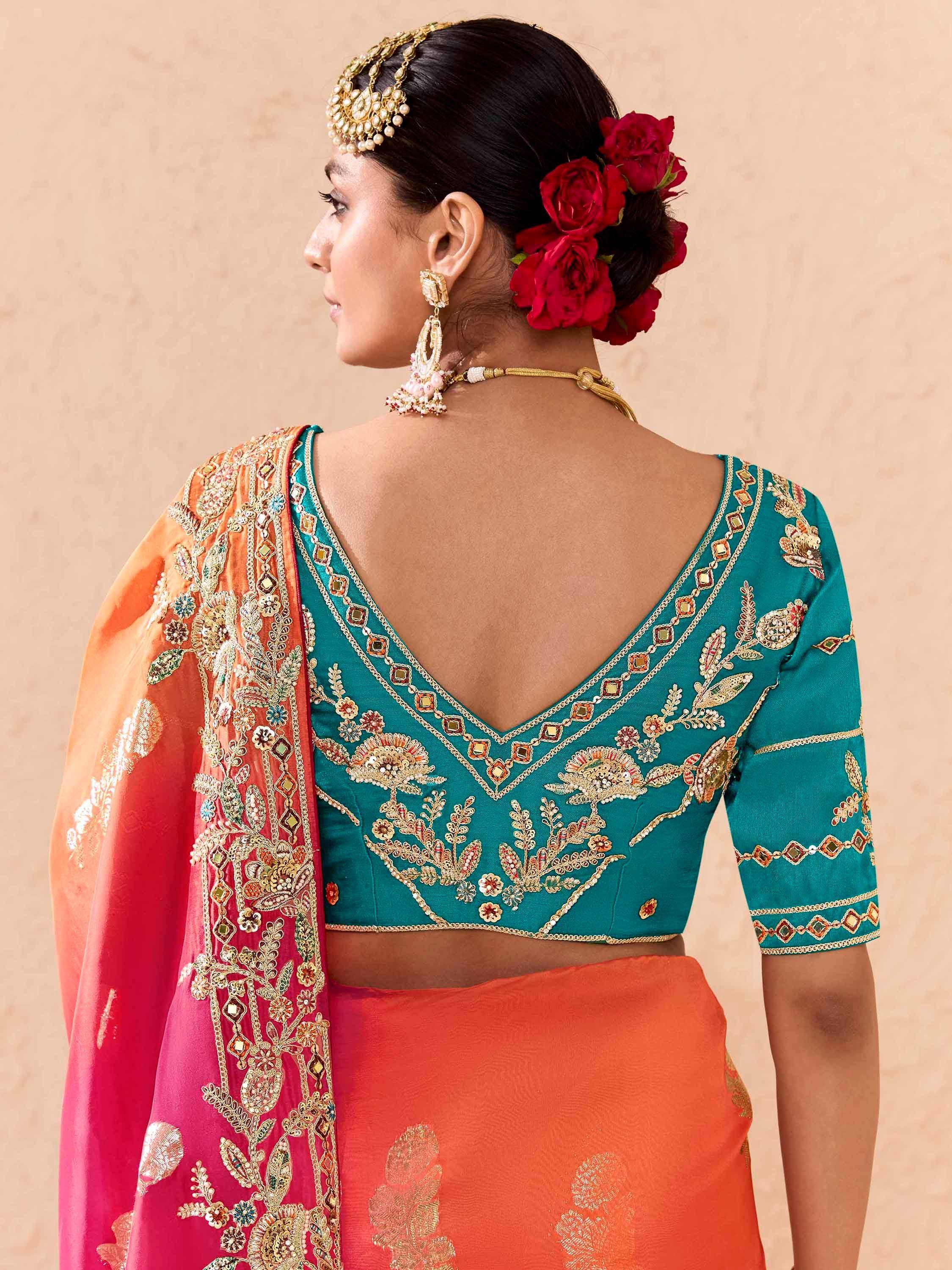 Teal embroidered blouse with orange saree, floral jewelry, and red rose hair accessory