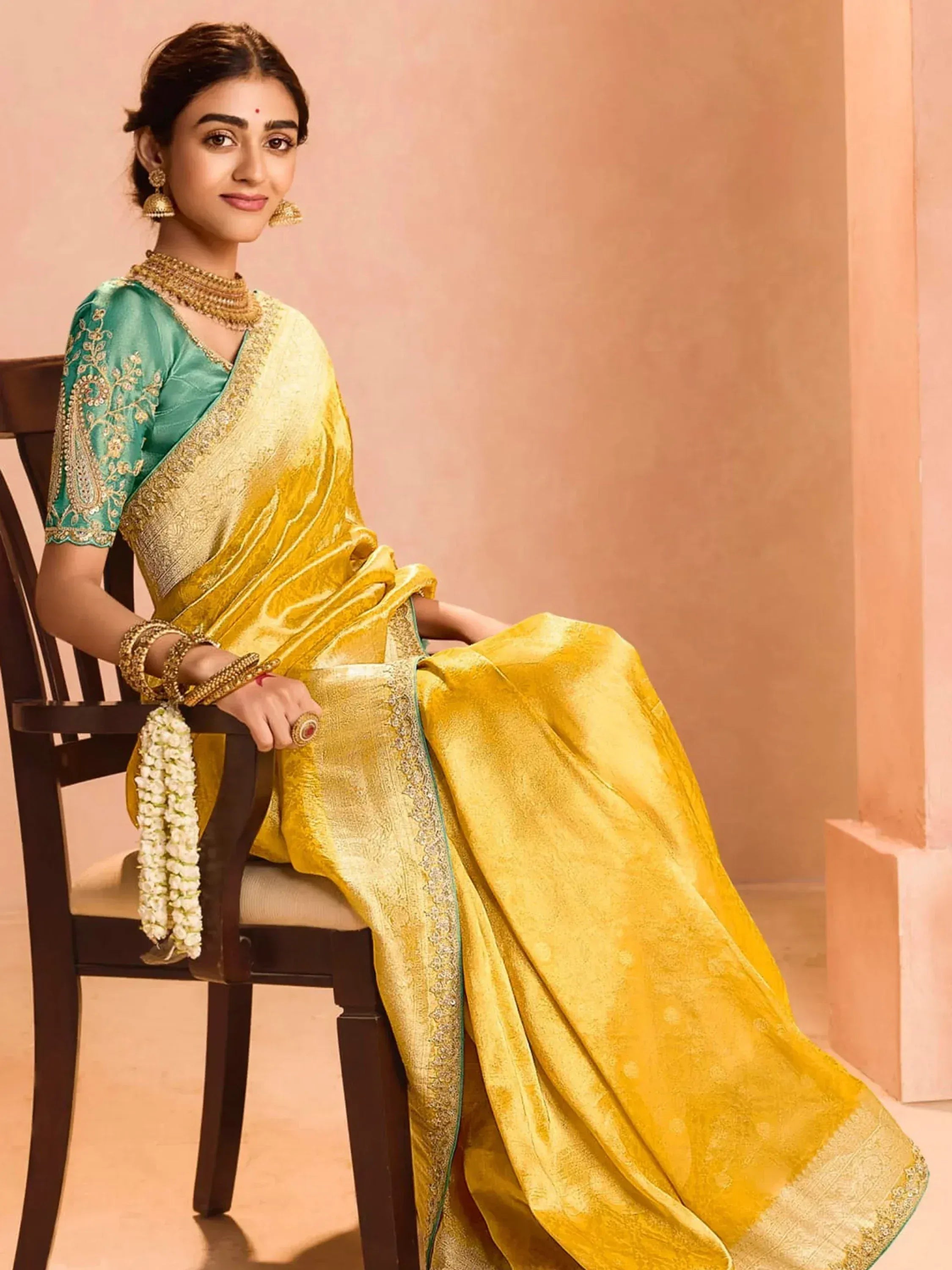 Yellow silk saree with green blouse, gold embroidery, and traditional Indian jewelry for festive occasions