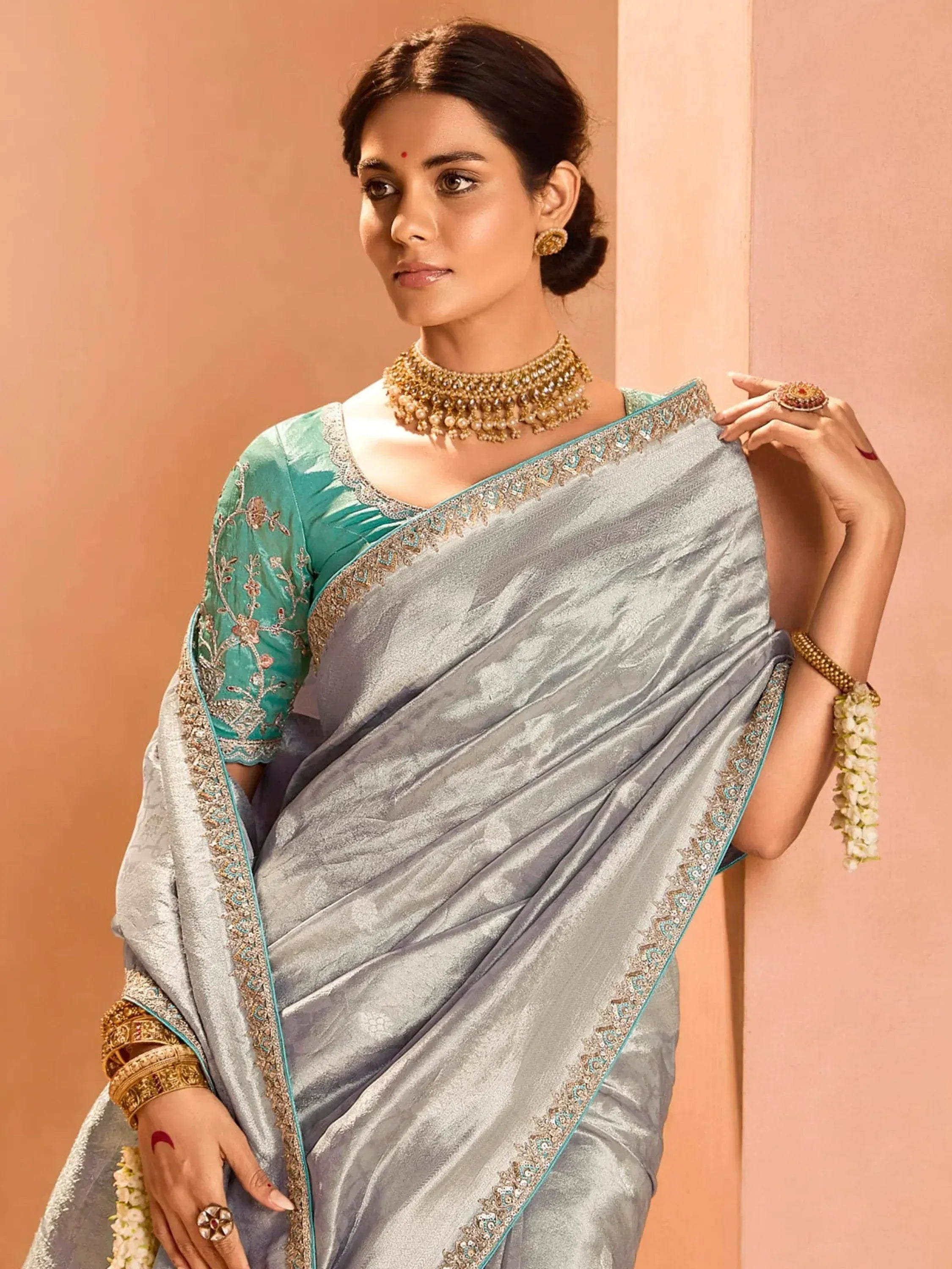 Elegant grey saree with teal blouse, intricate embroidery, and gold jewelry for Indian ethnic wear