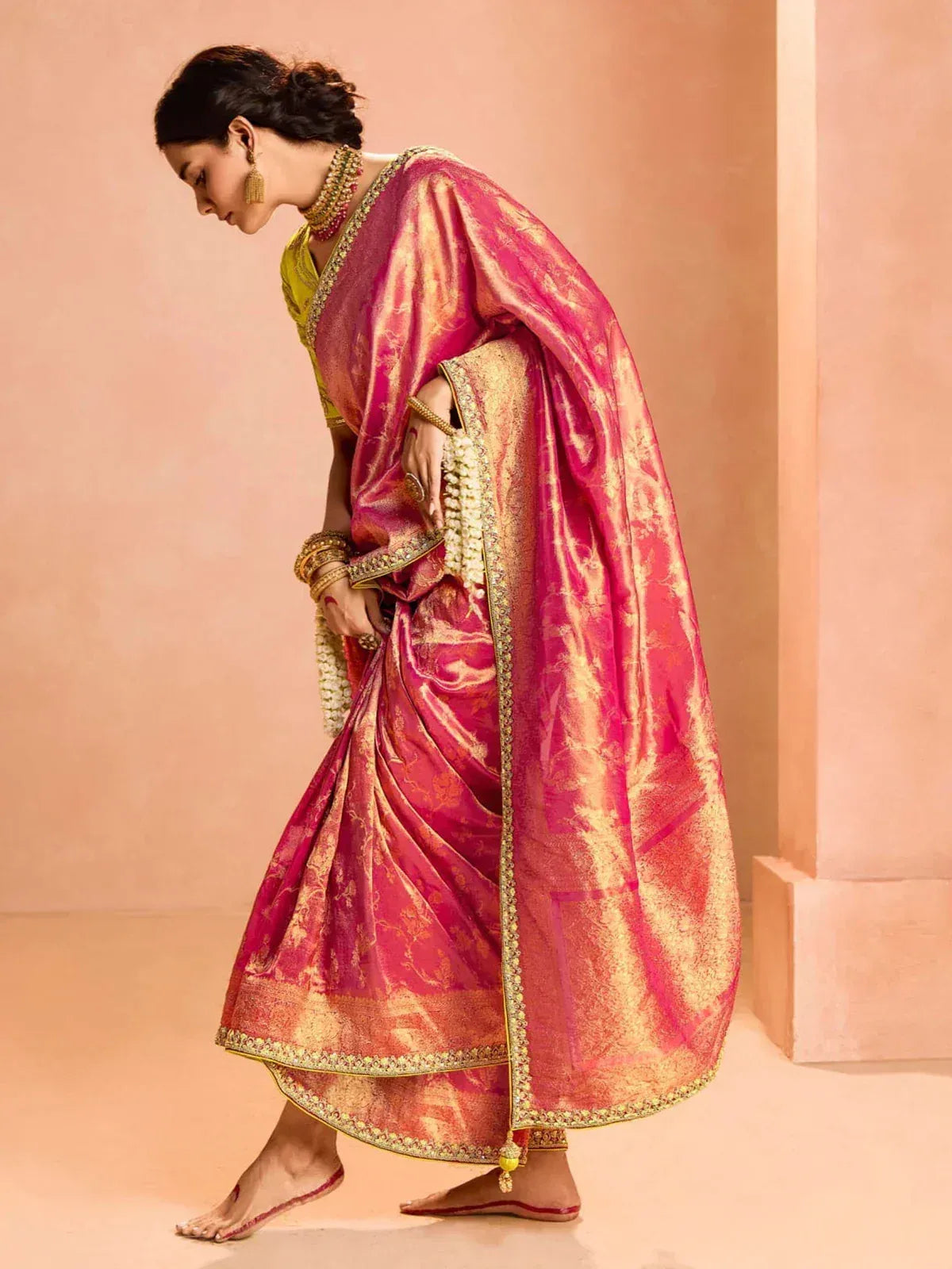 Woman in vibrant pink and gold designer saree with intricate embroidery, perfect for Indian ethnic occasions