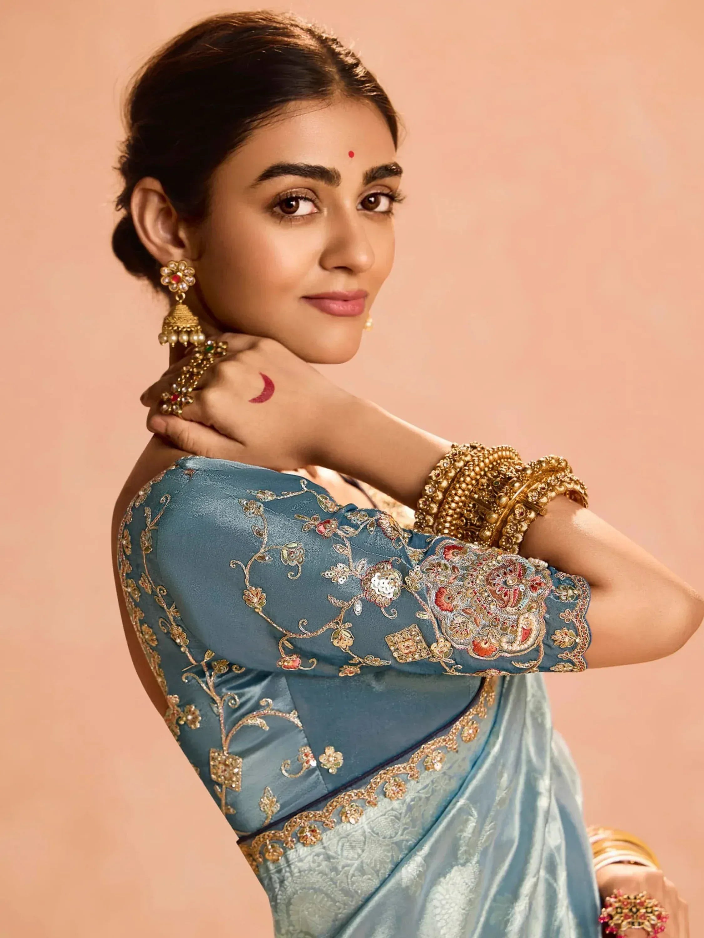 Blue embroidered saree blouse with gold floral work, paired with traditional Indian jewelry for festive occasions.