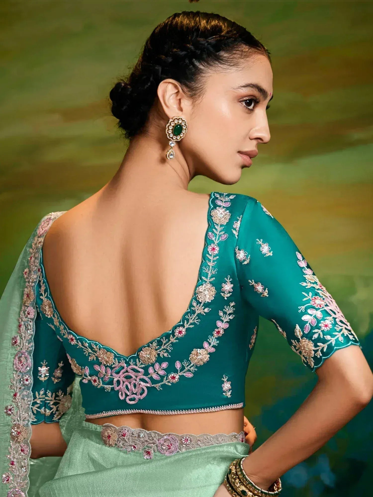 Teal embroidered blouse with floral detailing, backless design, paired with light green saree for Indian ethnic wear