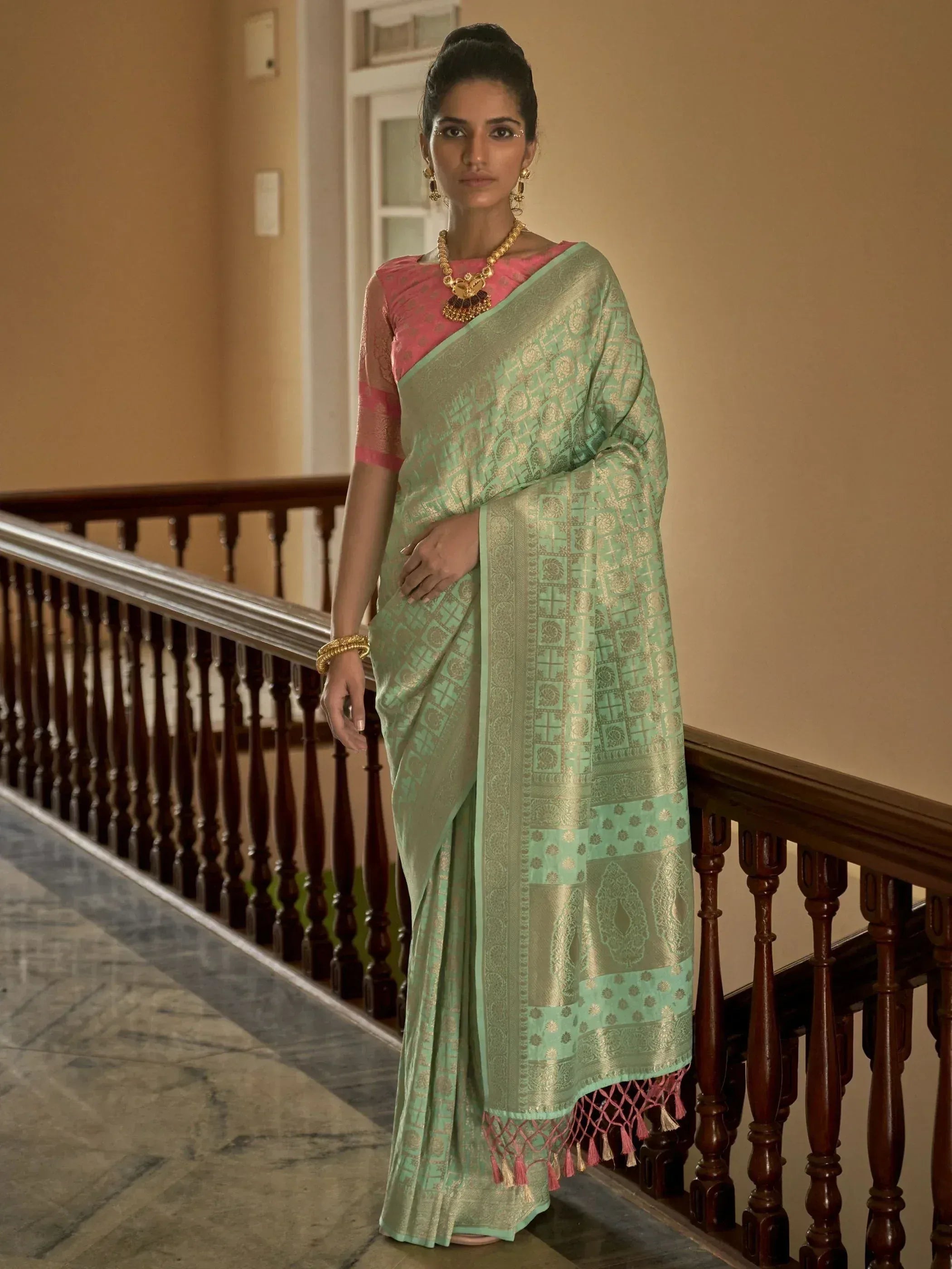 Woman in mint green designer saree with gold motifs and pink blouse, traditional Indian ethnic wear
