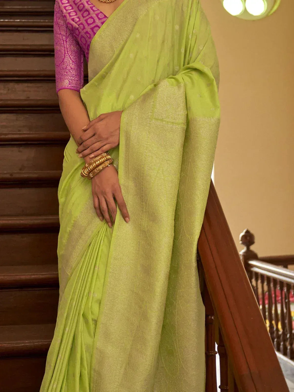 Lime green saree with gold motifs paired with purple blouse, styled for ethnic occasions