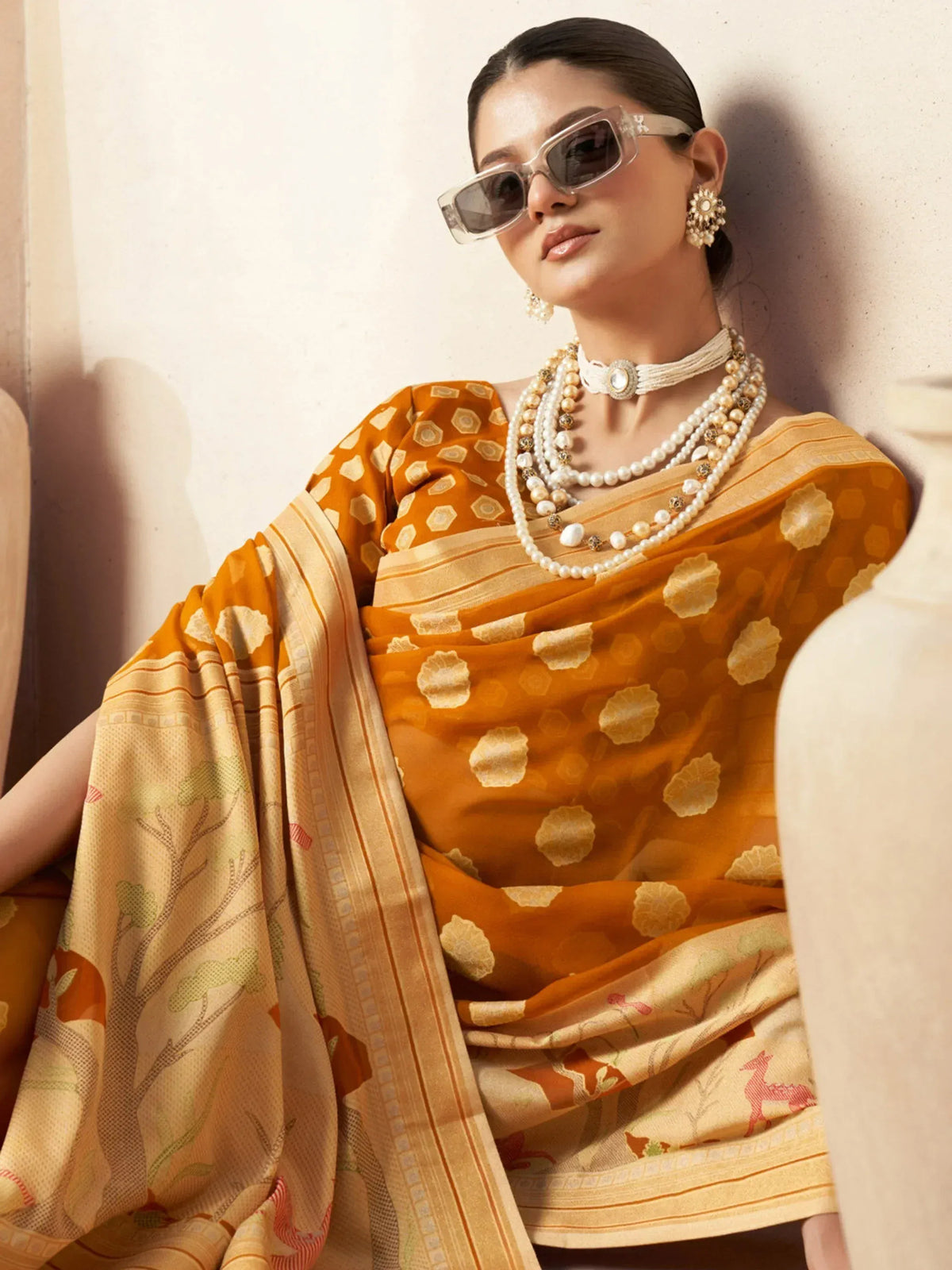Woman in mustard yellow ethnic saree with floral print, pearl jewelry, and sunglasses