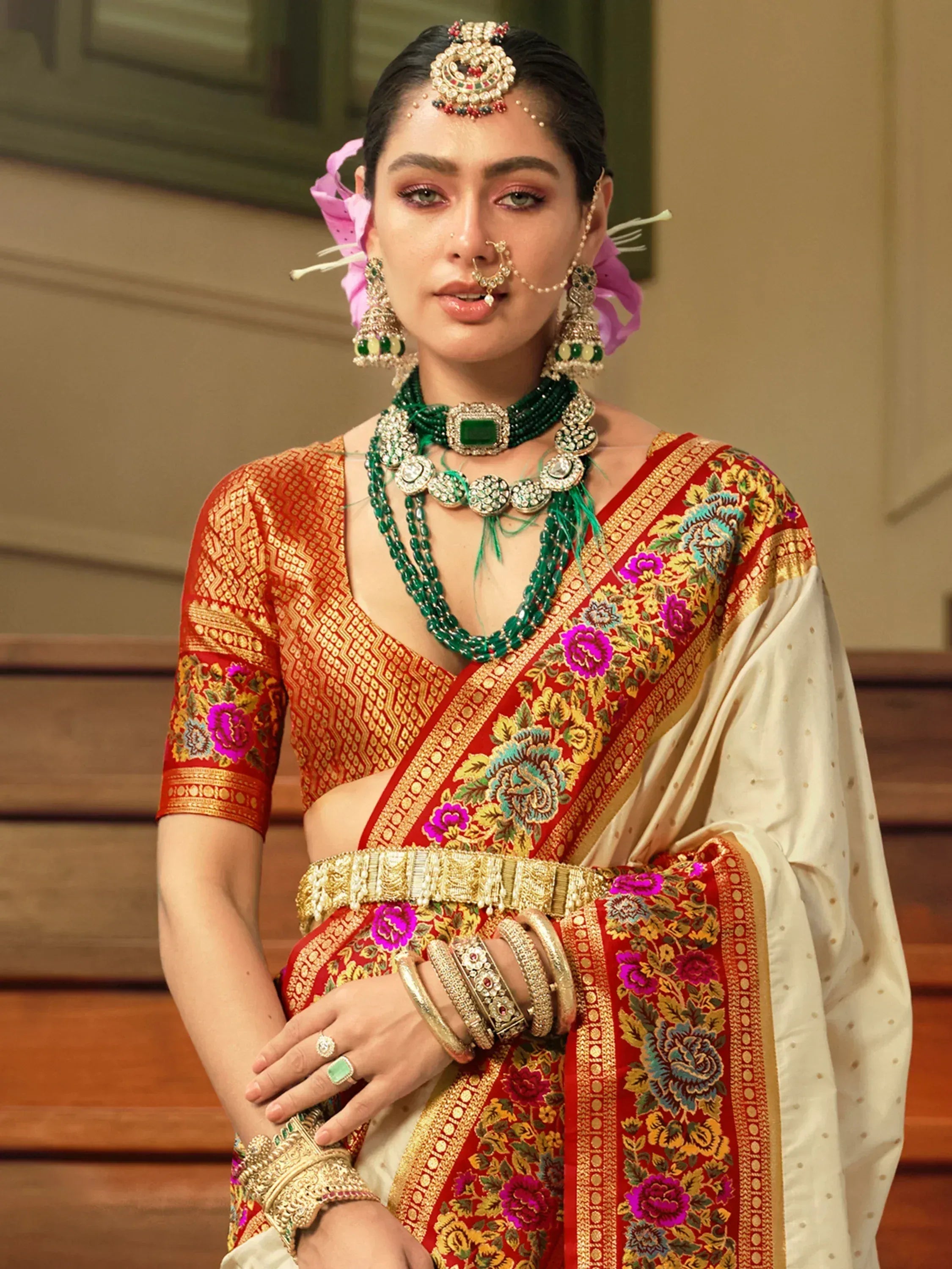 Woman in traditional Indian saree with floral embroidery, gold jewelry, and temple jewelry for weddings or festivals