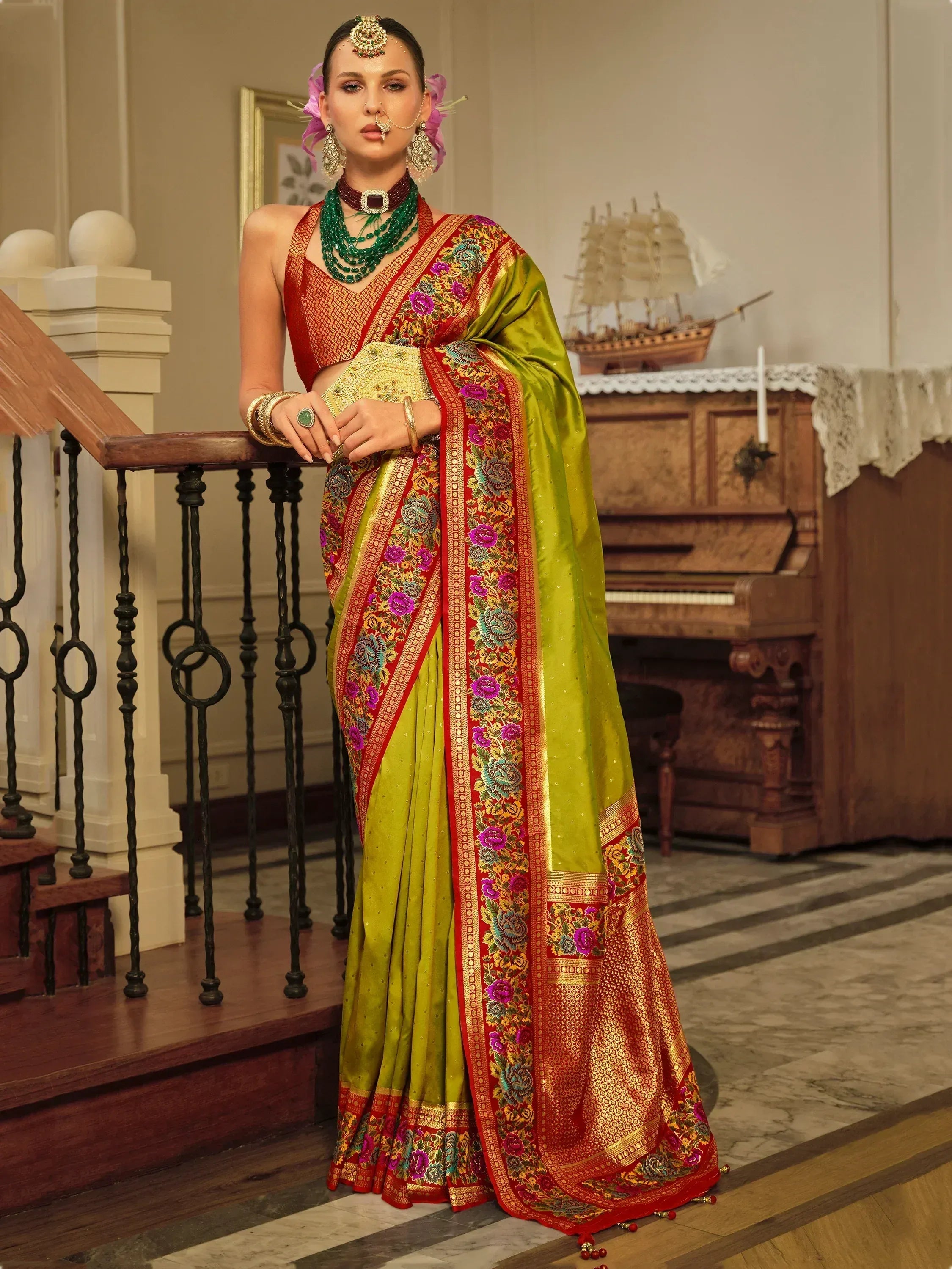 Woman in vibrant green and red embroidered saree with floral border, traditional Indian ethnic wear