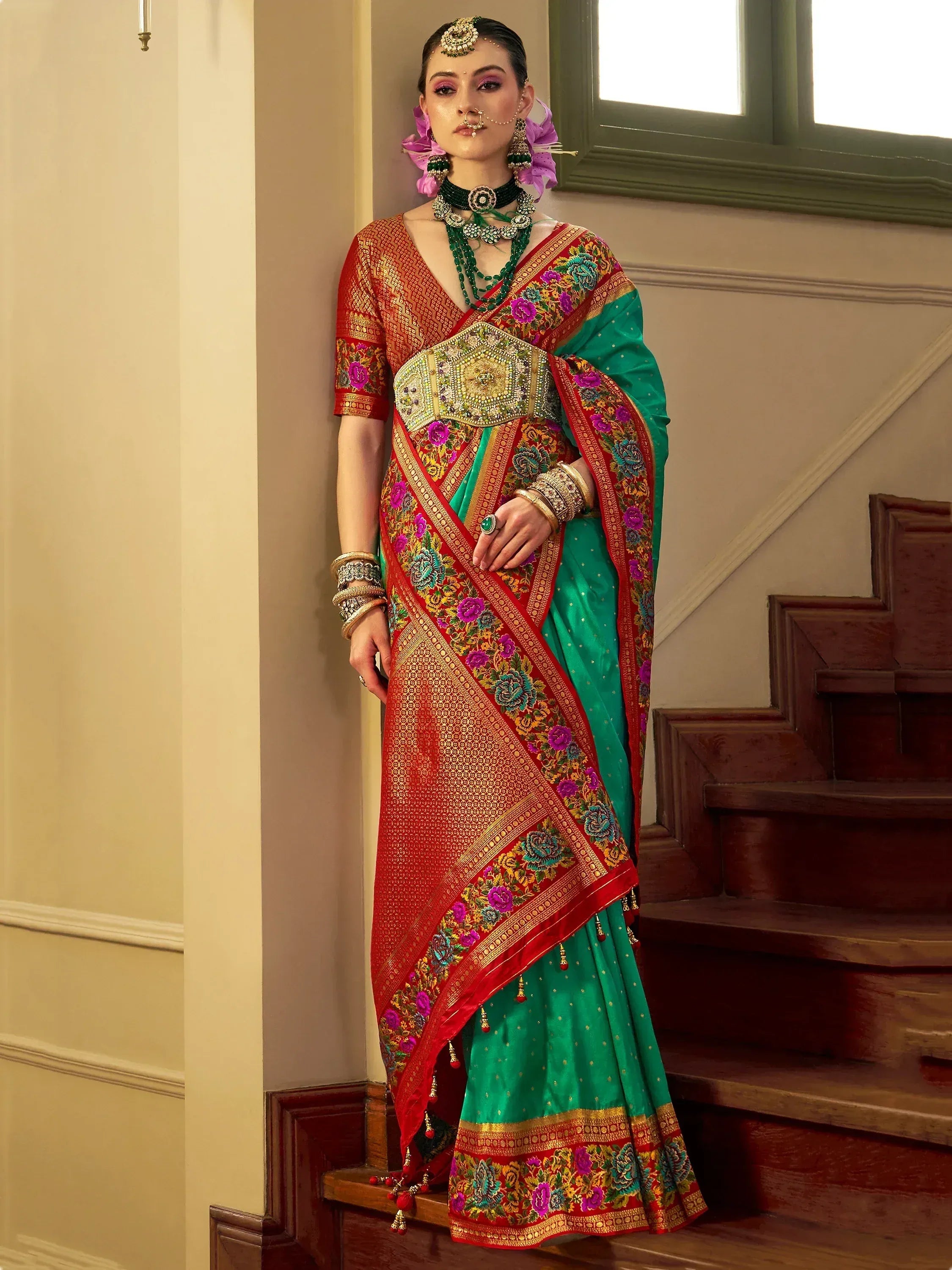 Woman in vibrant green and red embroidered saree with floral border, traditional Indian ethnic wear