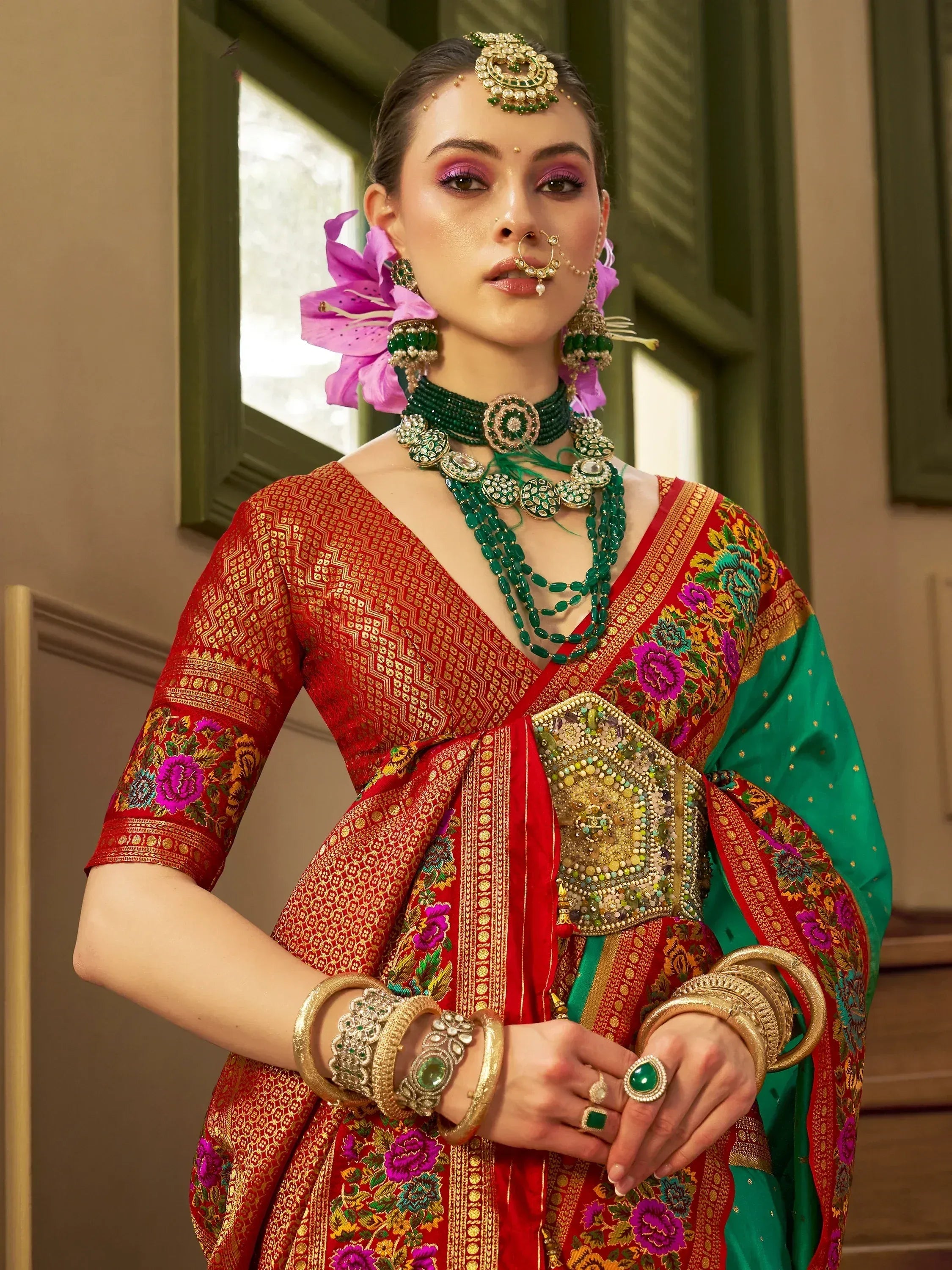 Red and green Indian ethnic saree with floral embroidery, traditional jewelry, and nose ring for festive occasions