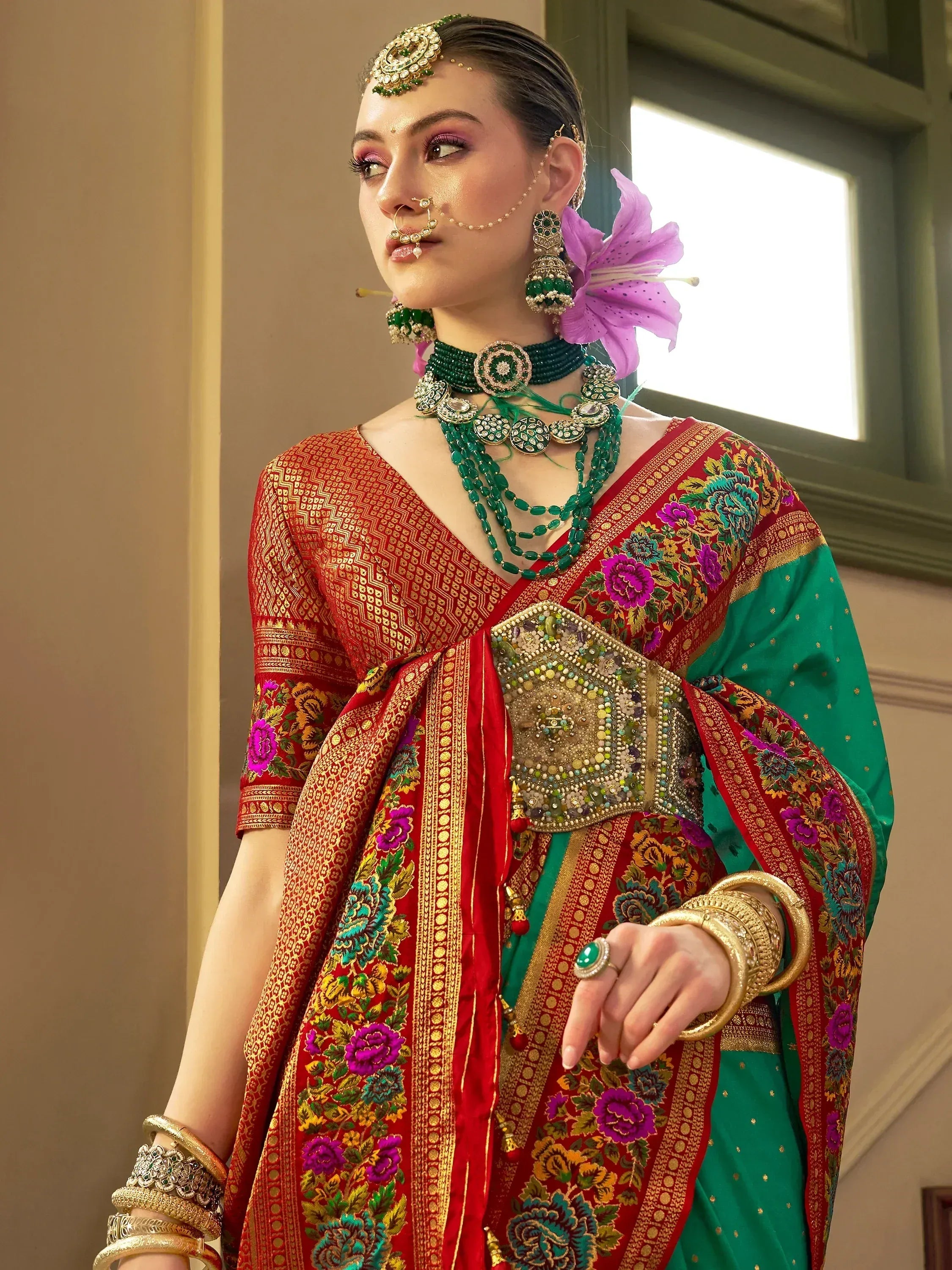 Woman in red and green embroidered Indian ethnic saree with floral patterns and traditional jewelry