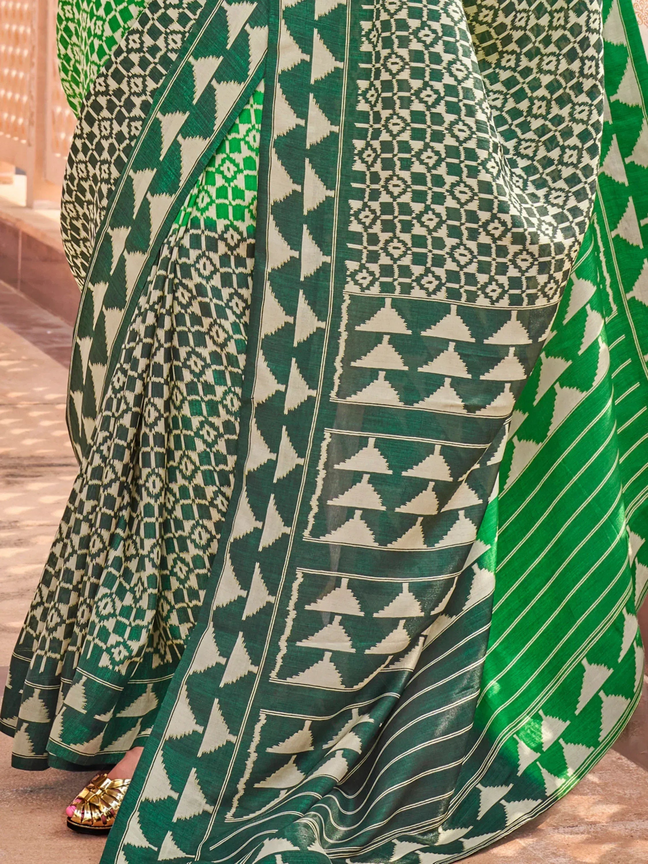 Green and white geometric patterned ethnic saree with intricate ikat design, perfect for traditional occasions.