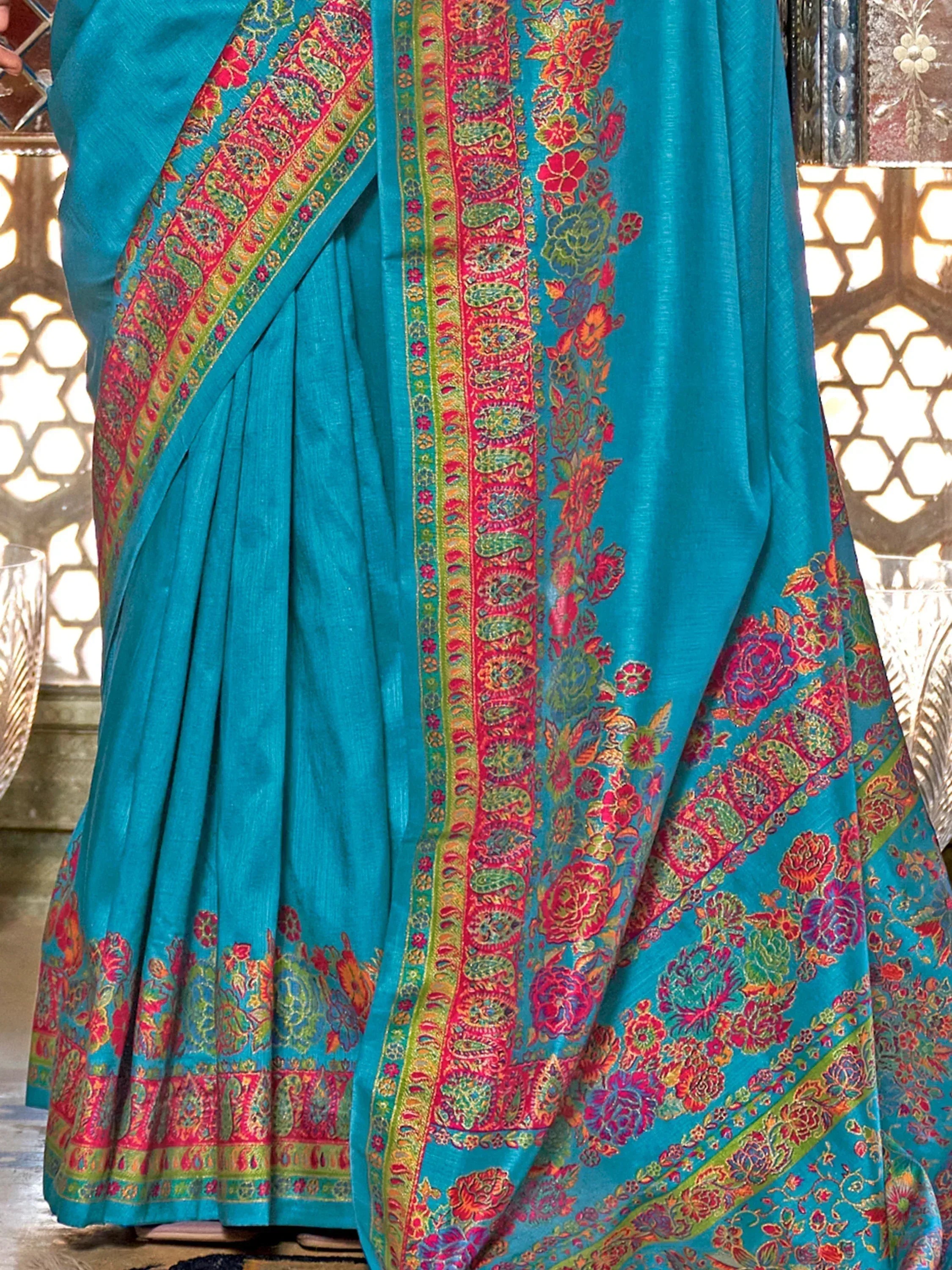 Turquoise saree with vibrant floral and paisley border, perfect for Indian ethnic wear occasions