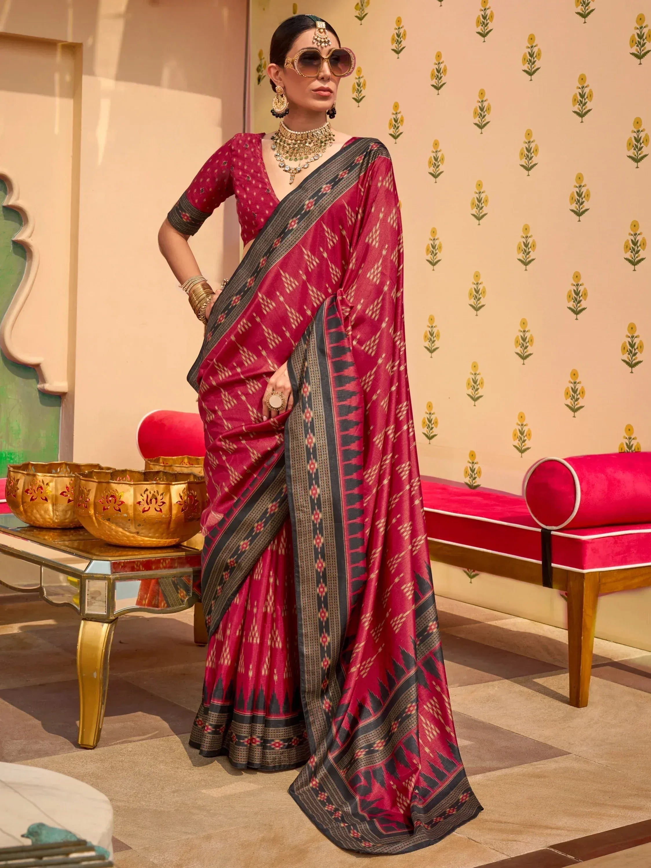 Elegant maroon saree with black border and geometric print, paired with gold jewelry and sunglasses for festive Indian ethnic wear.