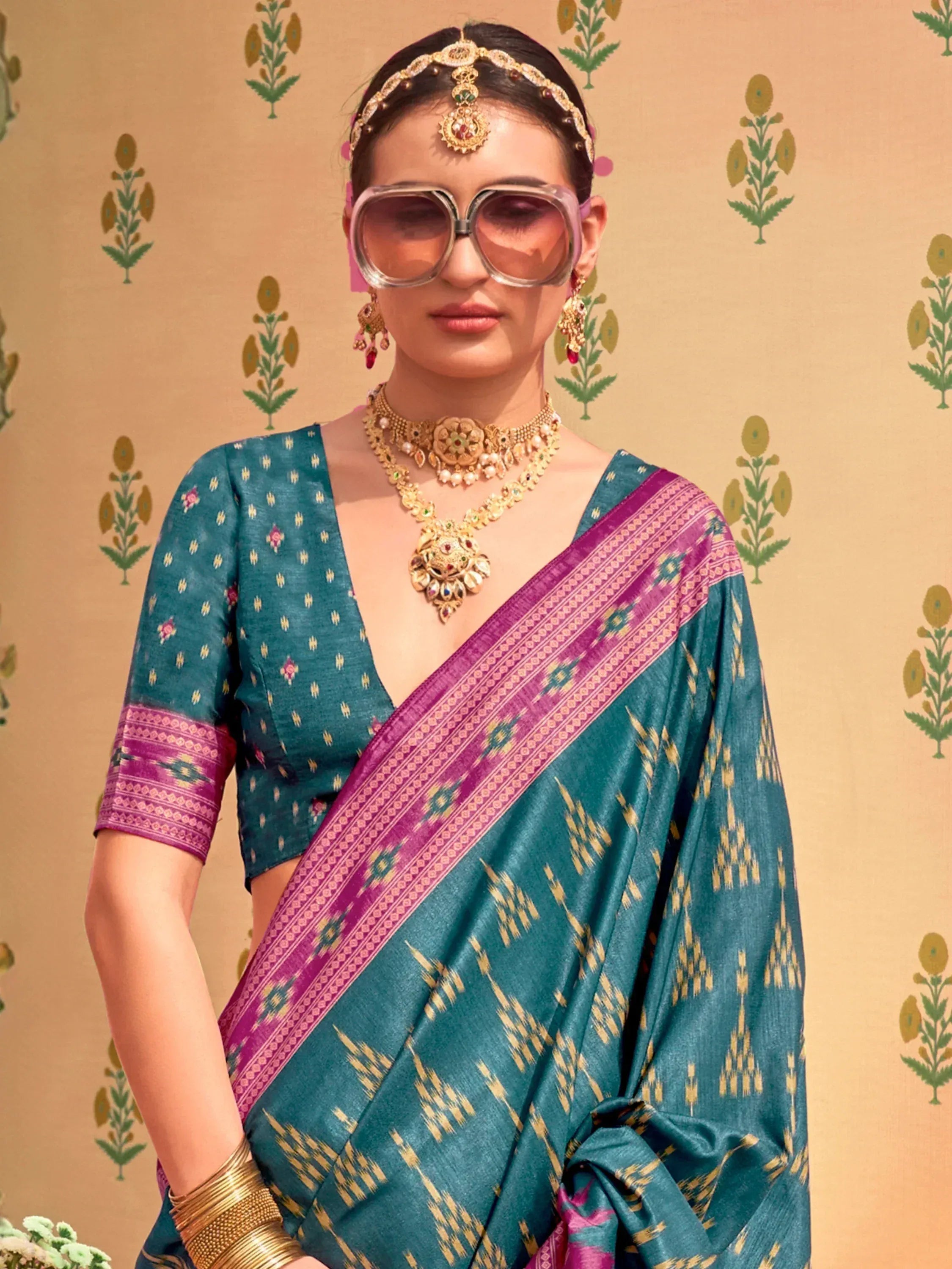 Teal ikat saree with purple border, gold jewelry, and statement sunglasses for ethnic fashion