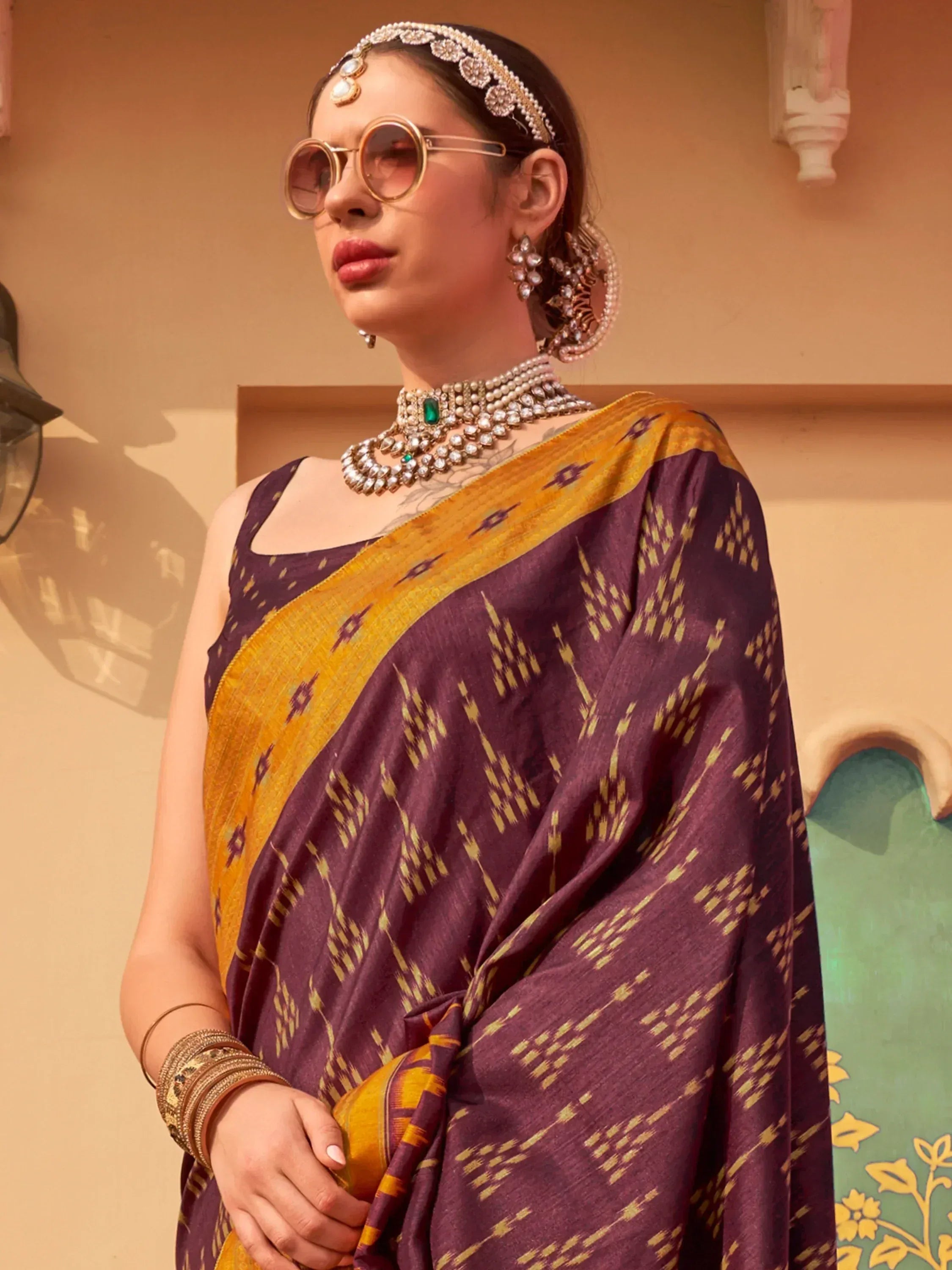 Woman in purple and gold ikat saree with traditional jewelry and sunglasses, Indian ethnic wear