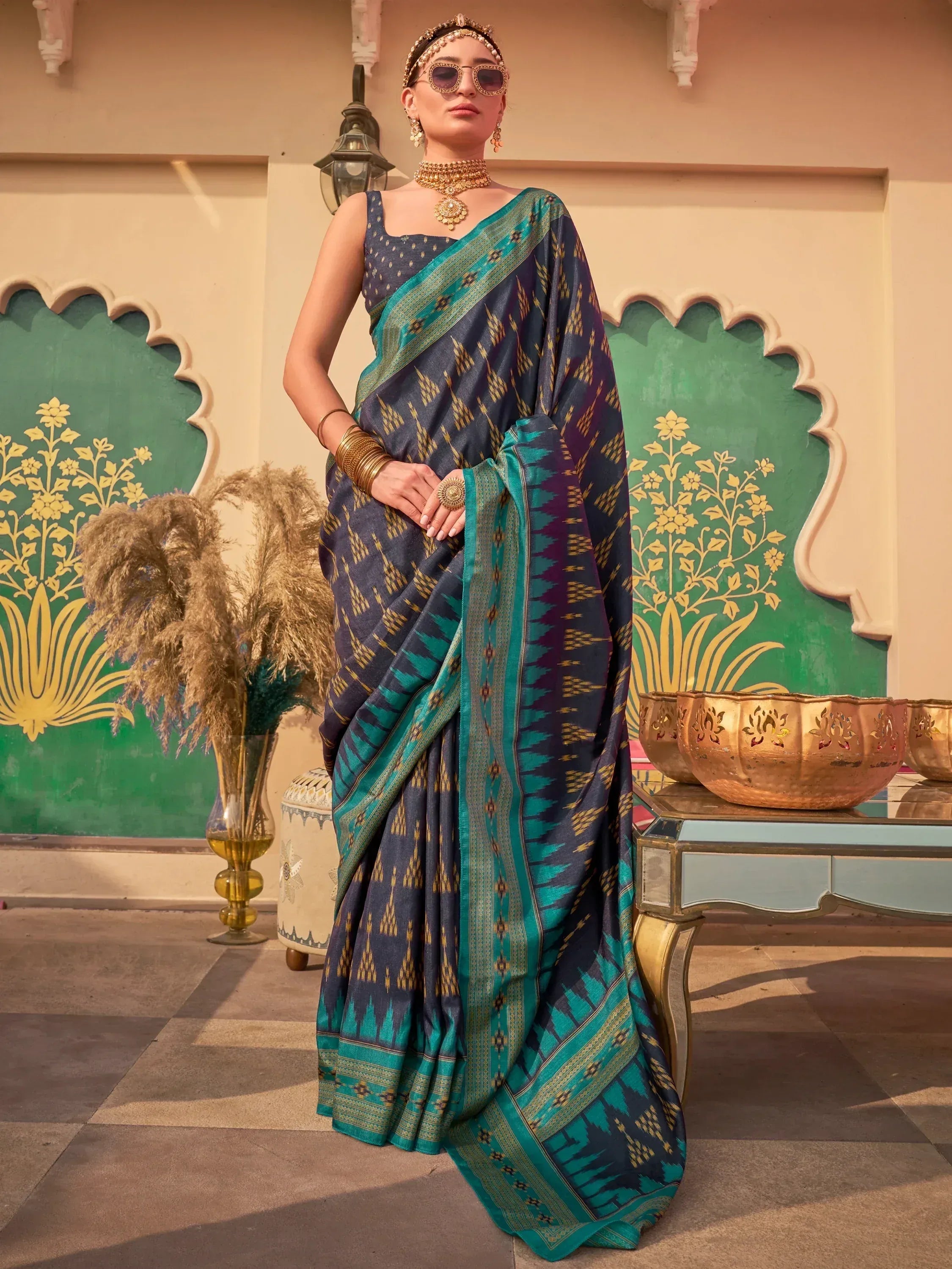 Woman in navy blue and teal ikat saree with gold jewelry, styled for Indian ethnic wear