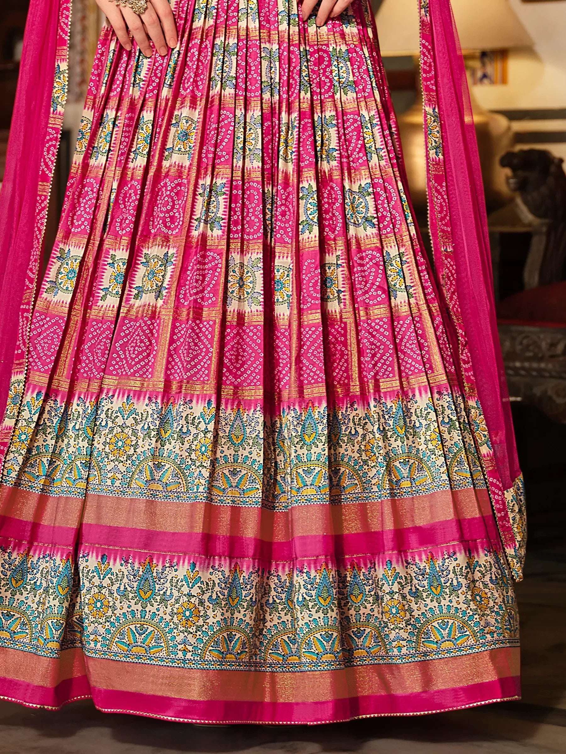 Pink printed lehenga with gold, blue, and yellow ethnic patterns and pleated skirt detail
