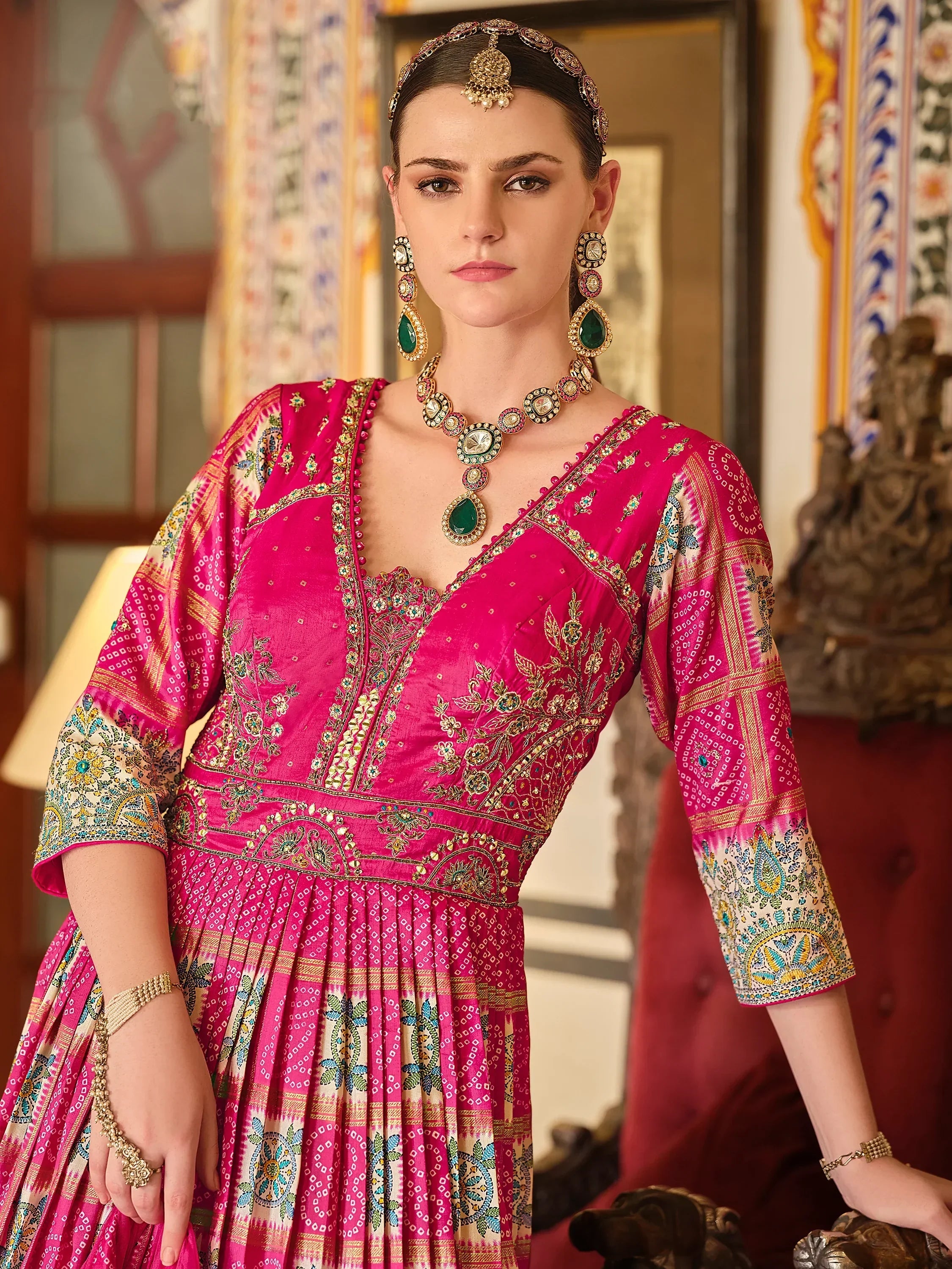 Woman in traditional pink Indian embroidered ethnic gown with green jewelry