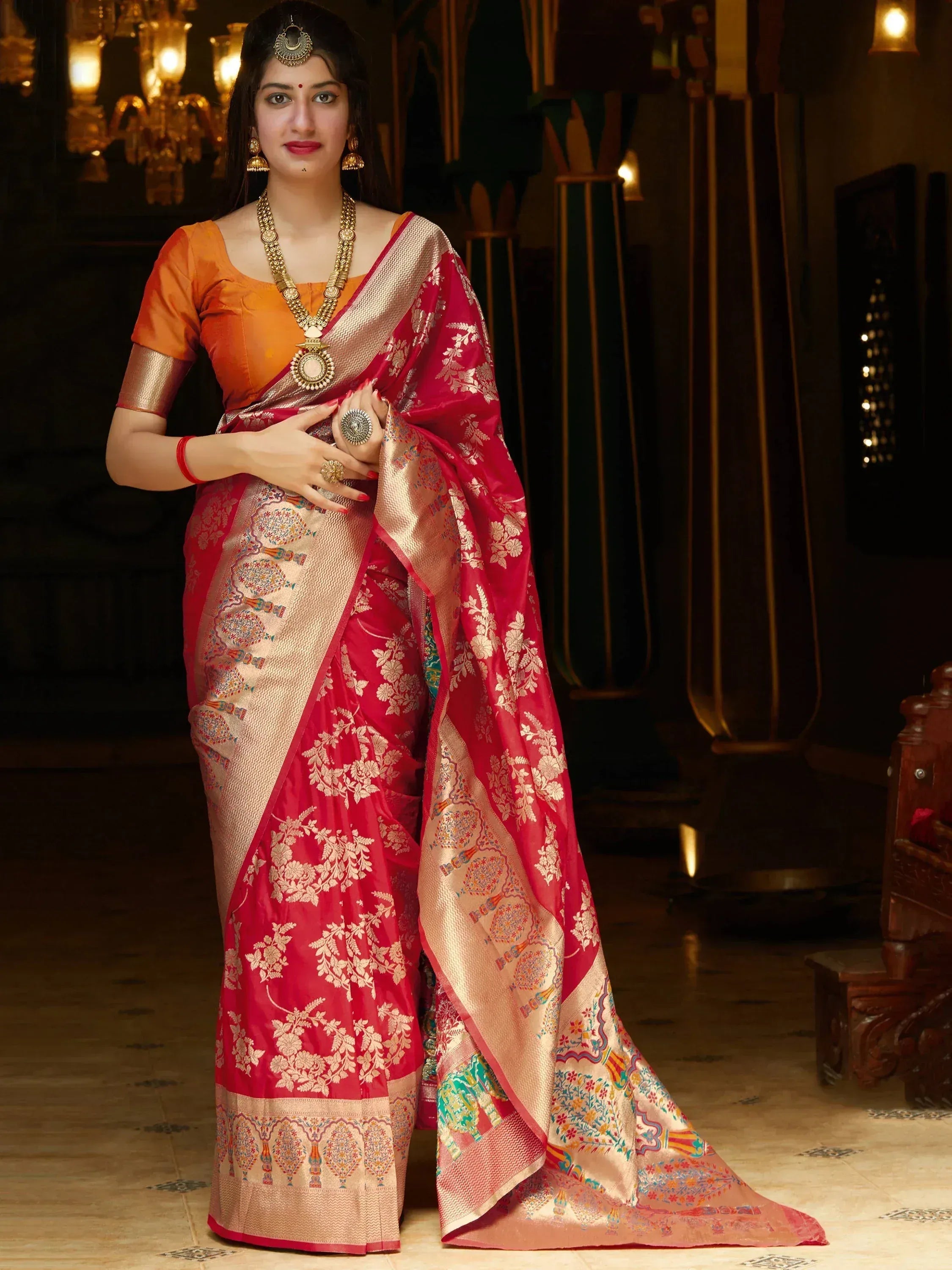 Woman in red floral Banarasi saree with gold border, orange blouse, traditional Indian jewelry