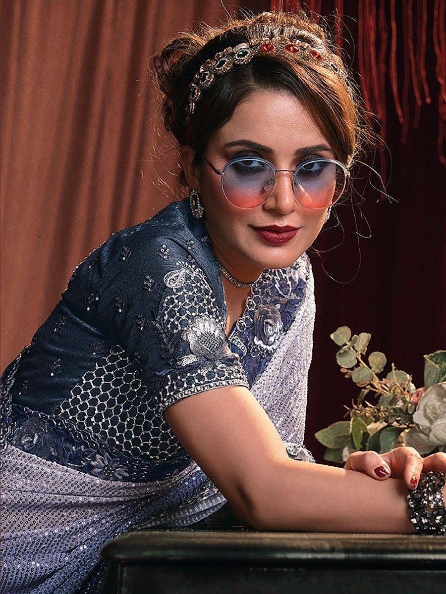 Stylish woman in blue embroidered ethnic gown with sequins, headpiece, and sunglasses
